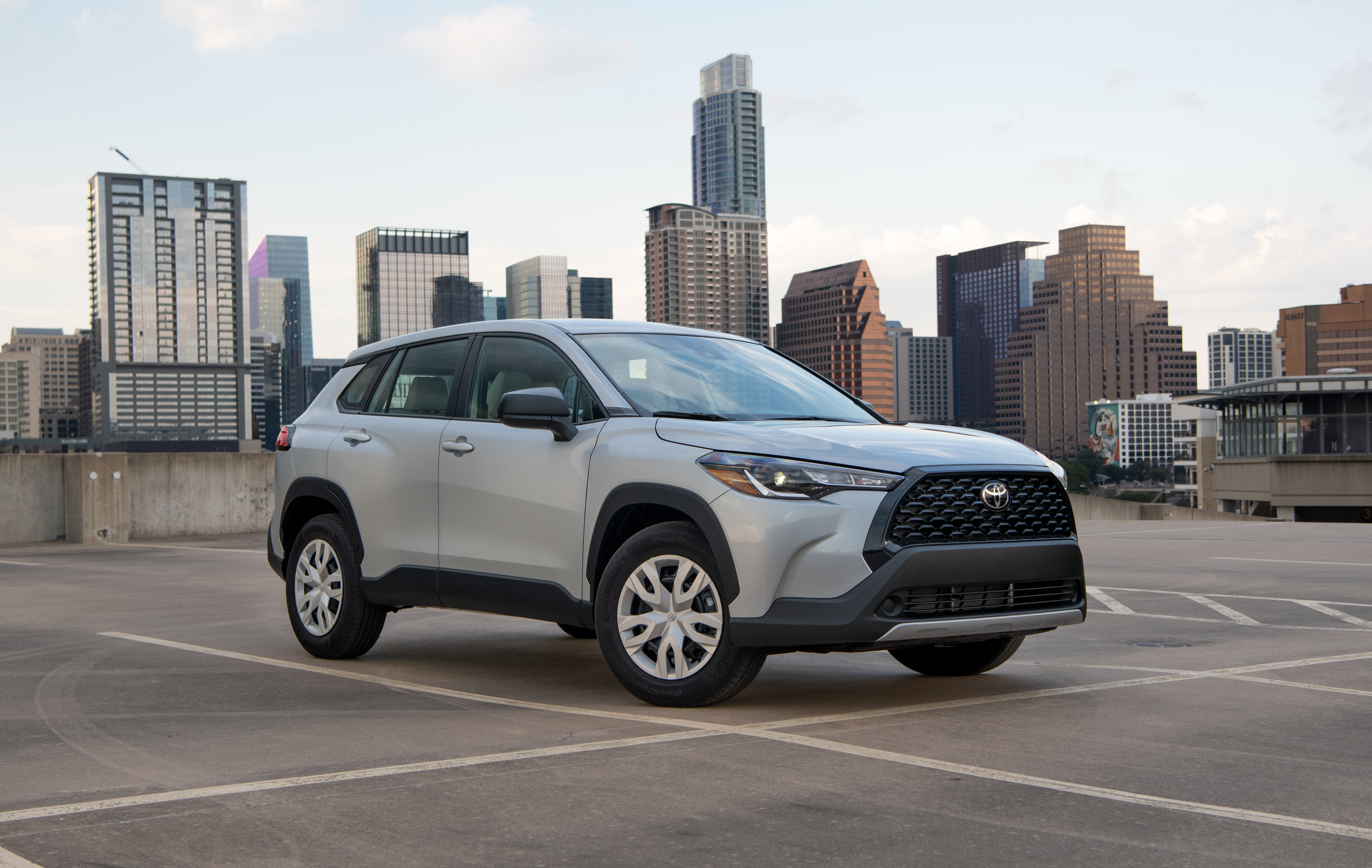 Silver Toyota Corolla Cross SUV with city skyline HD Wallpaper