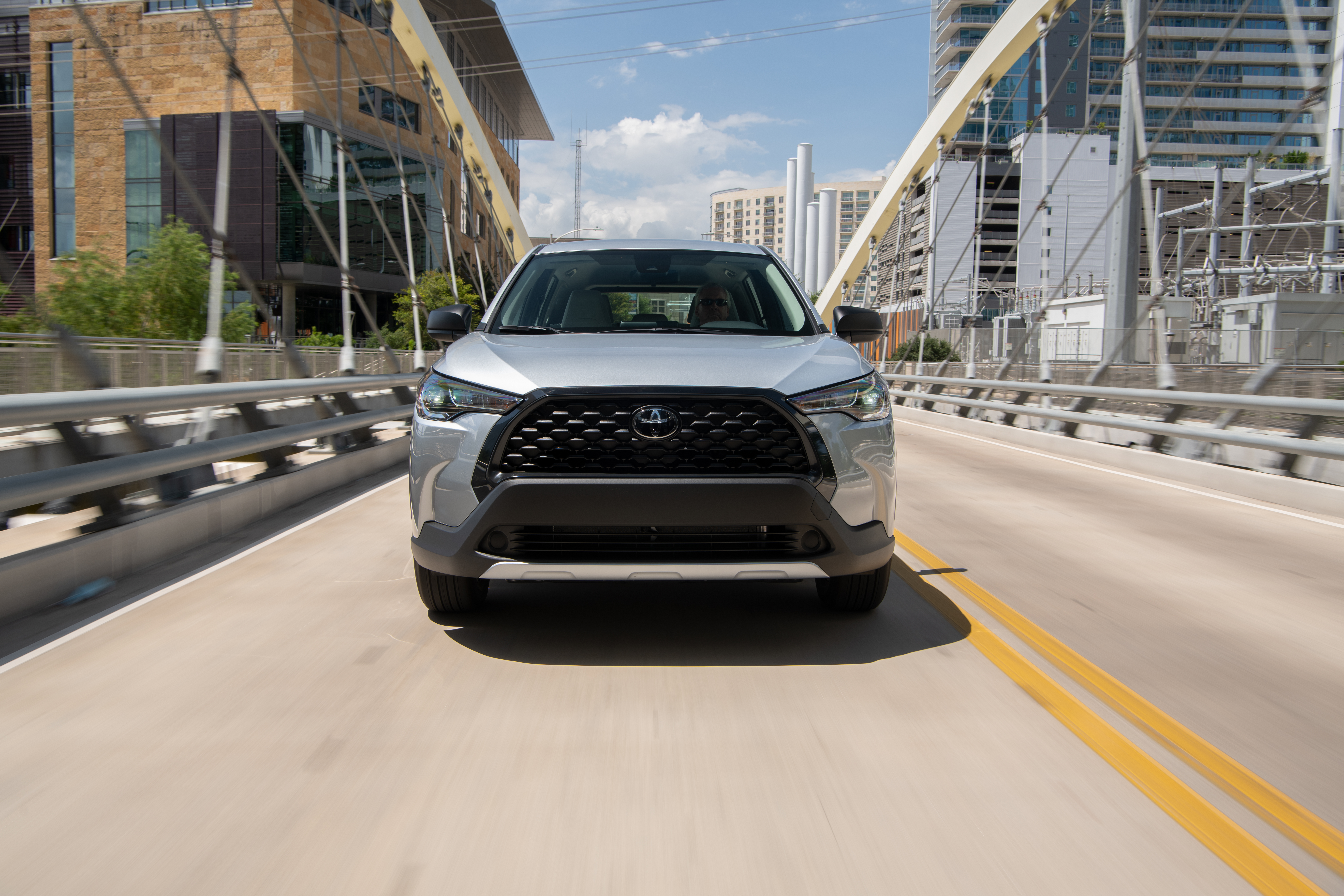 Silver Toyota Corolla Cross SUV driving on bridge HD Wallpaper