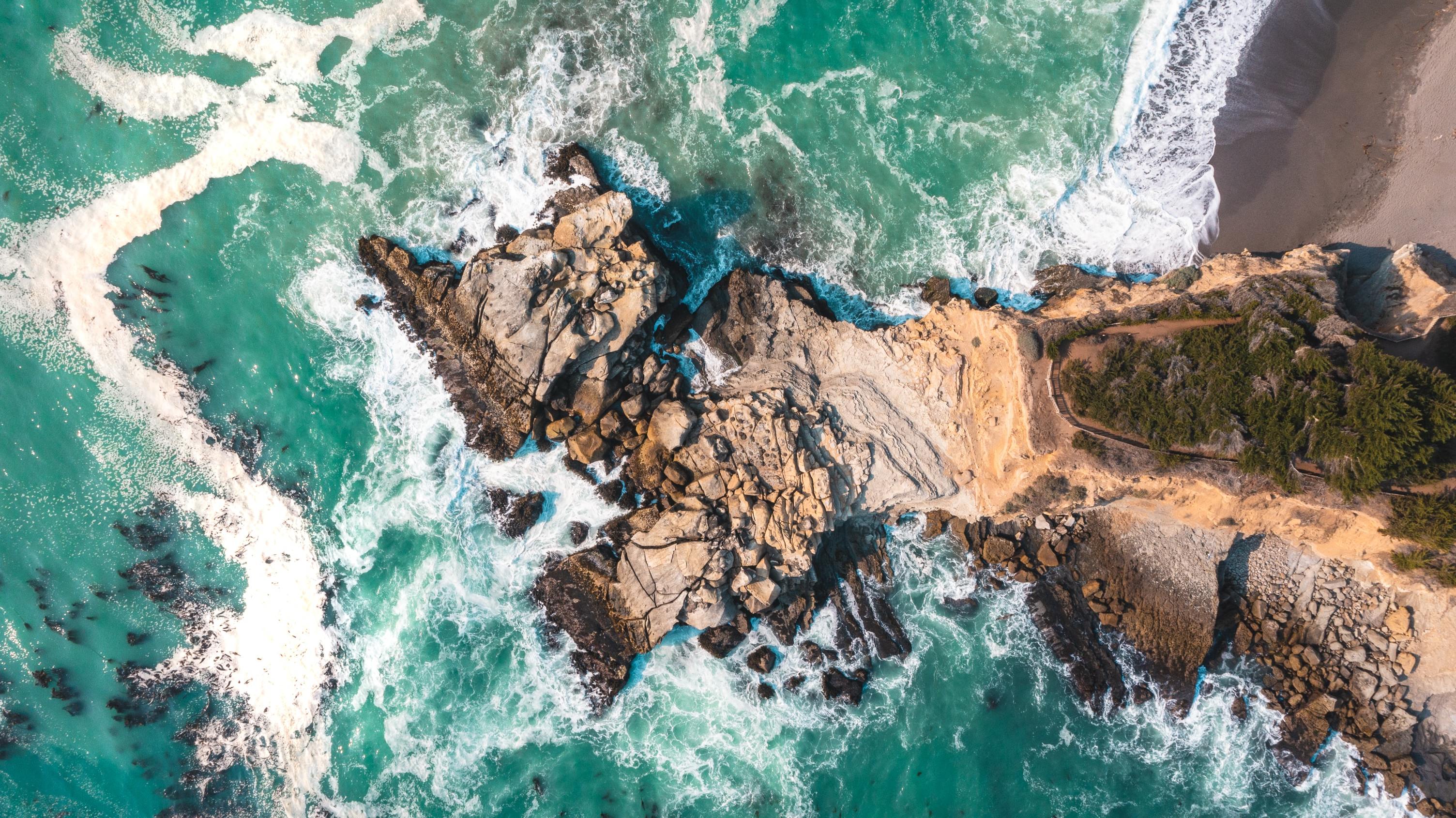 Aerial view of a beautiful turquoise ocean and rocky beach HD Wallpaper