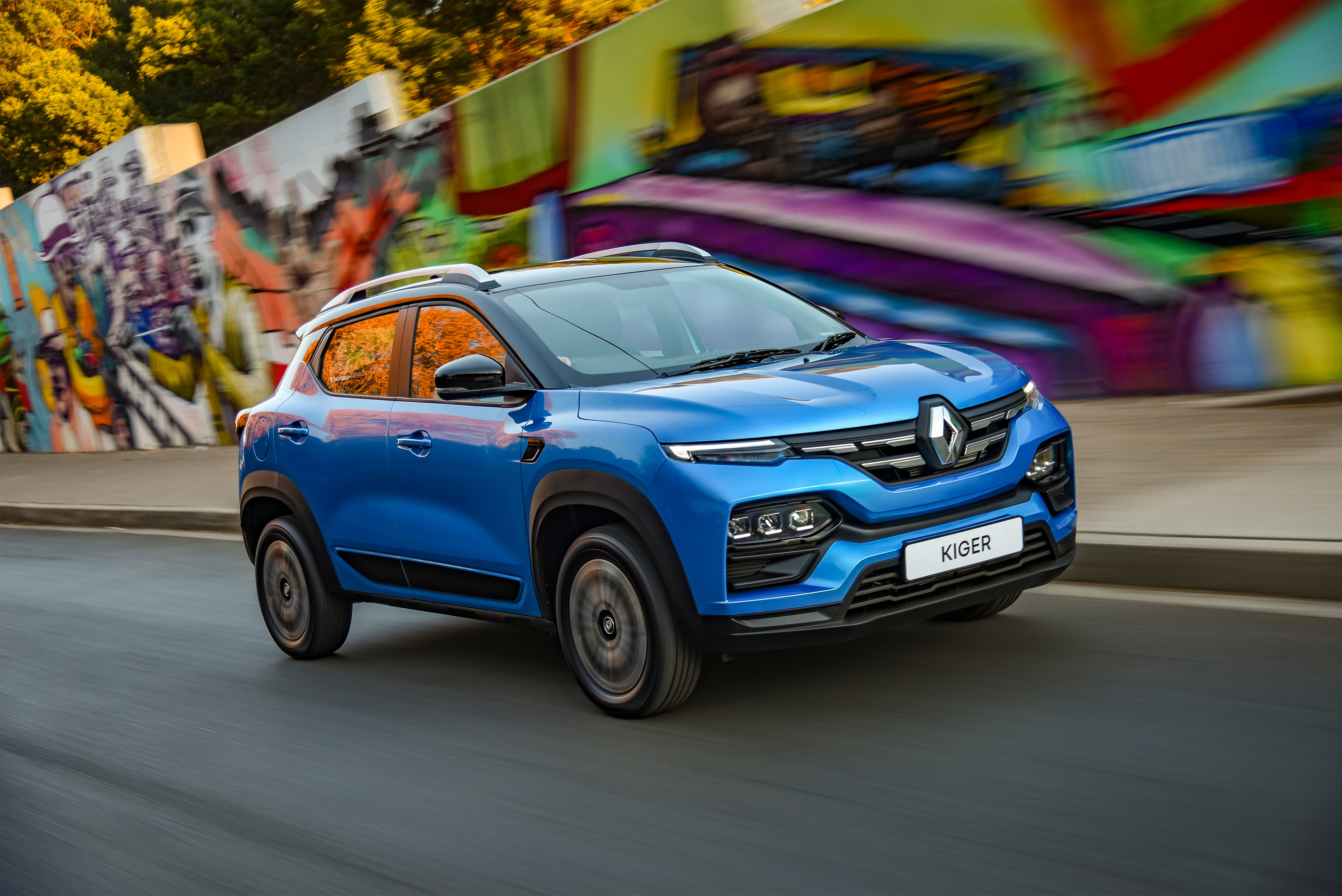 Blue Renault Kiger SUV driving past graffiti wall HD Wallpaper