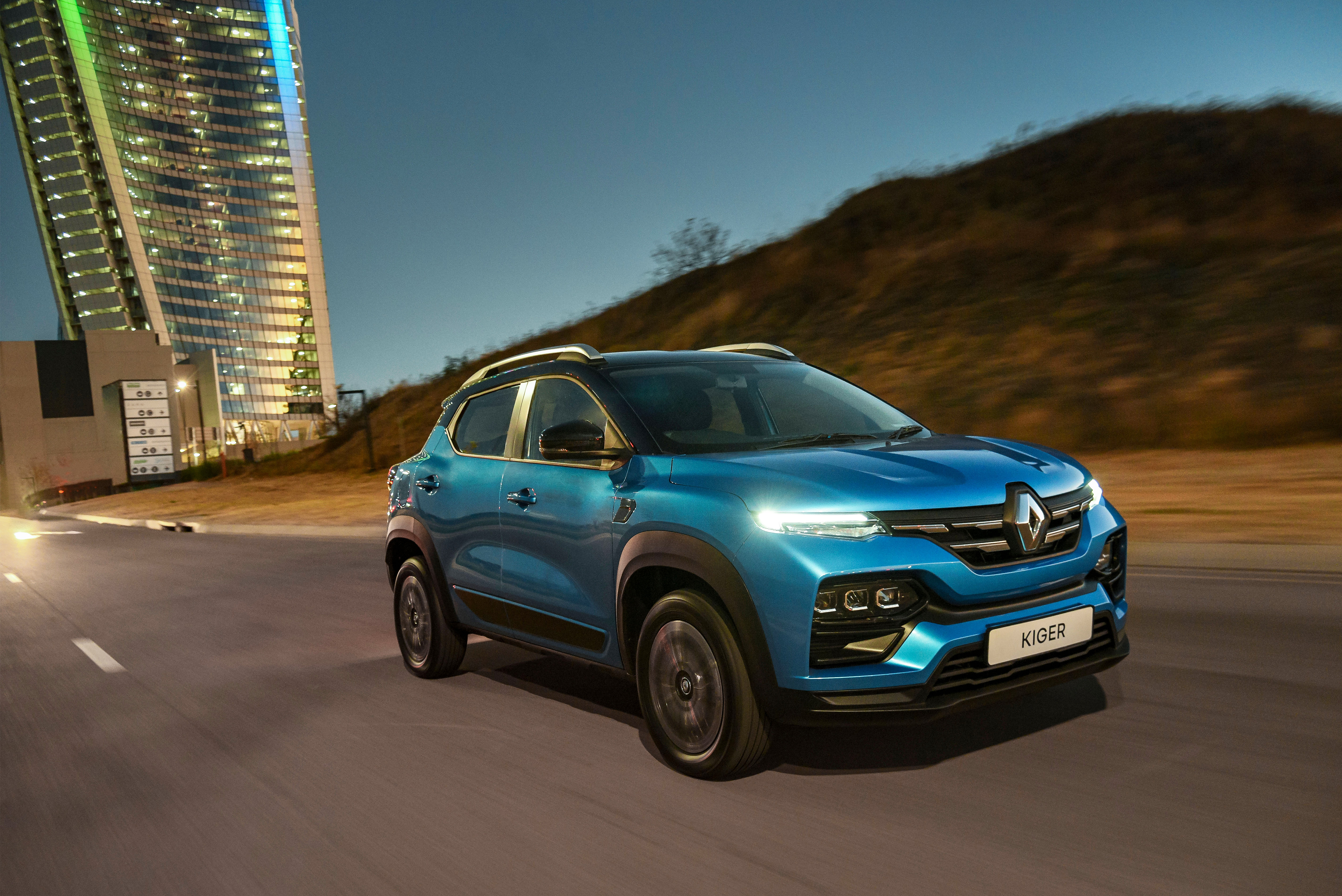 Renault Kiger SUV driving at night by illuminated building HD Wallpaper