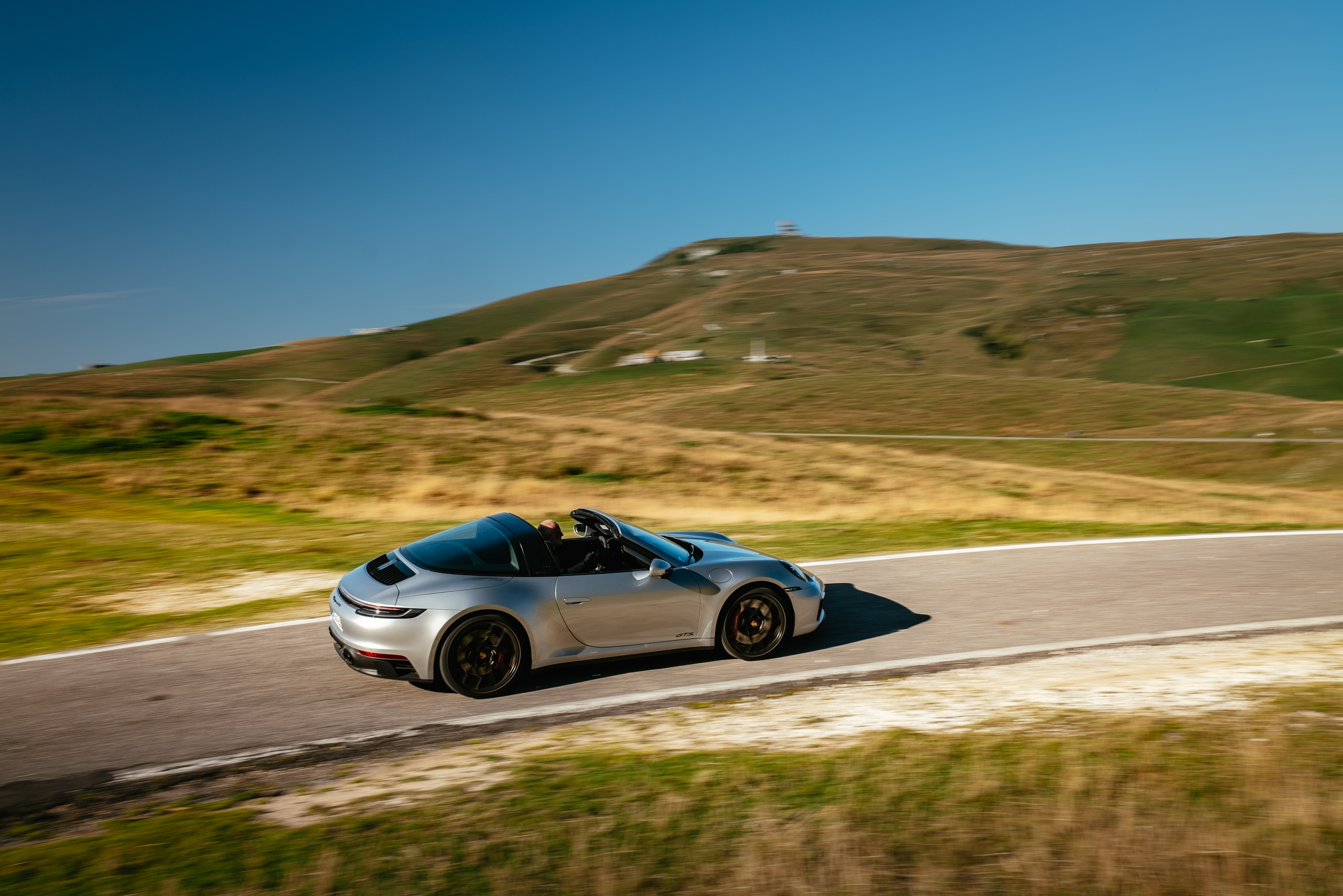 Porsche 911 Targa 4 GTS cruising through a hilly landscape HD Wallpaper