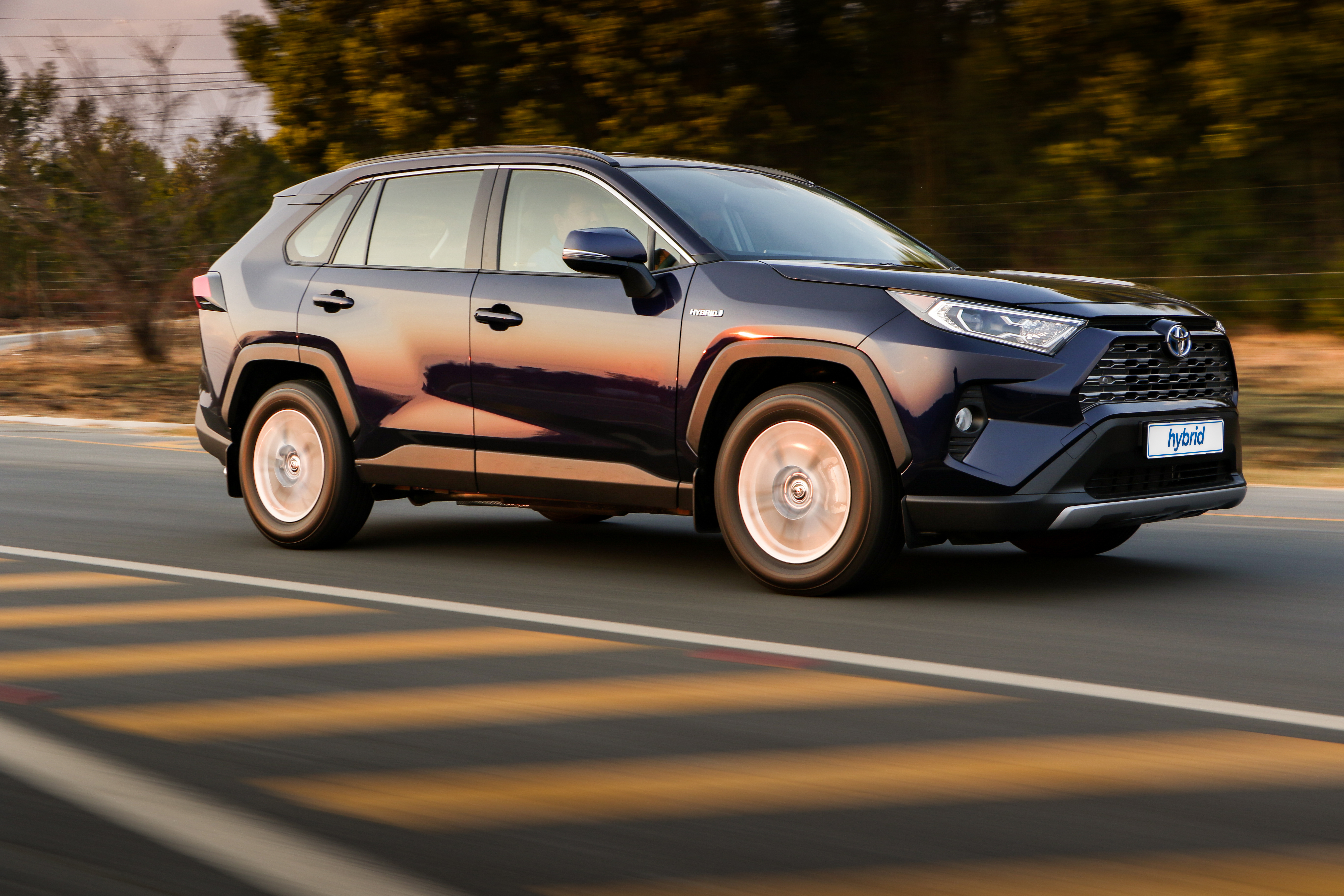 Dark blue Toyota RAV4 Hybrid SUV driving on road HD Wallpaper