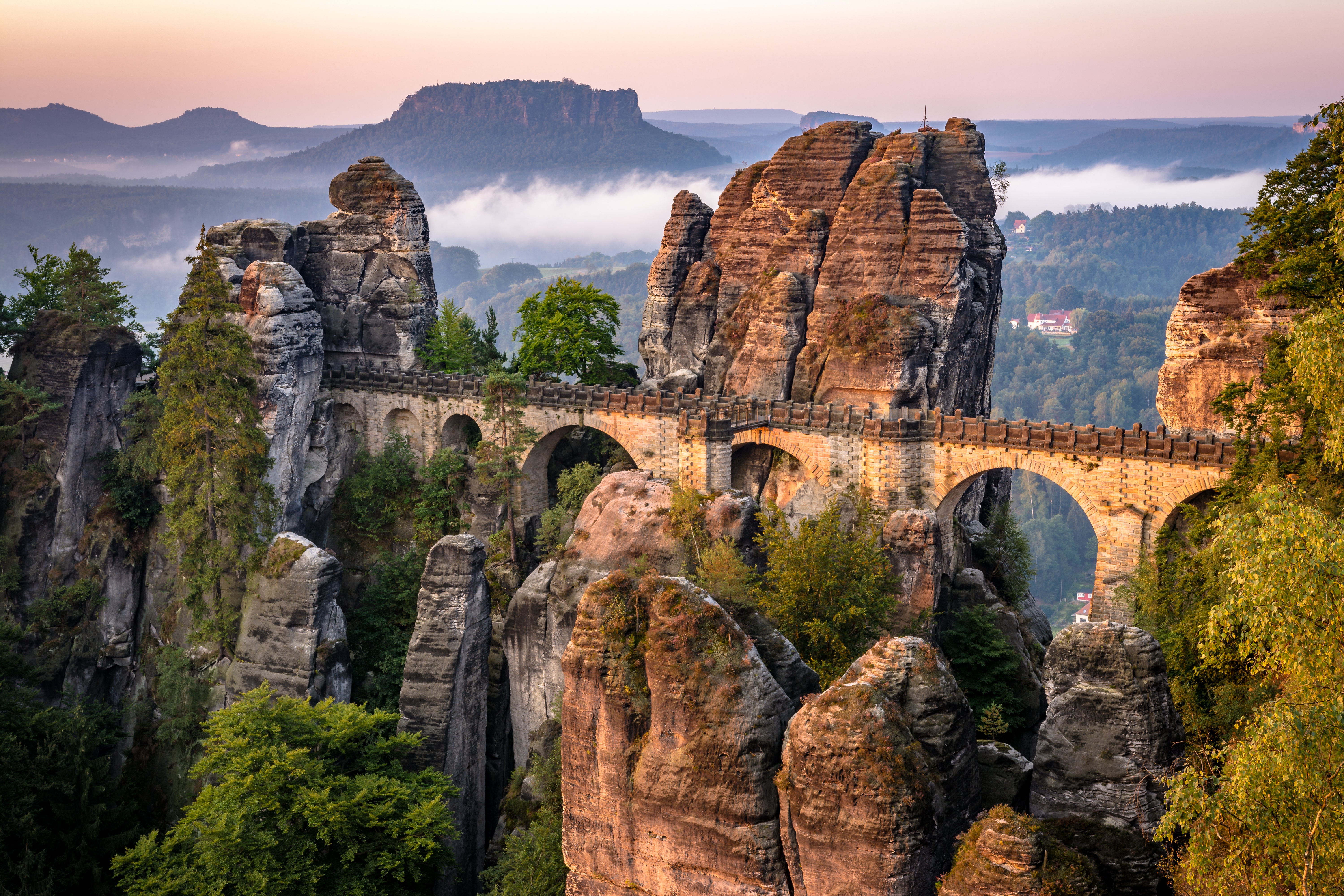 Ancient stone bridge among towering rock formations at sunrise HD Wallpaper