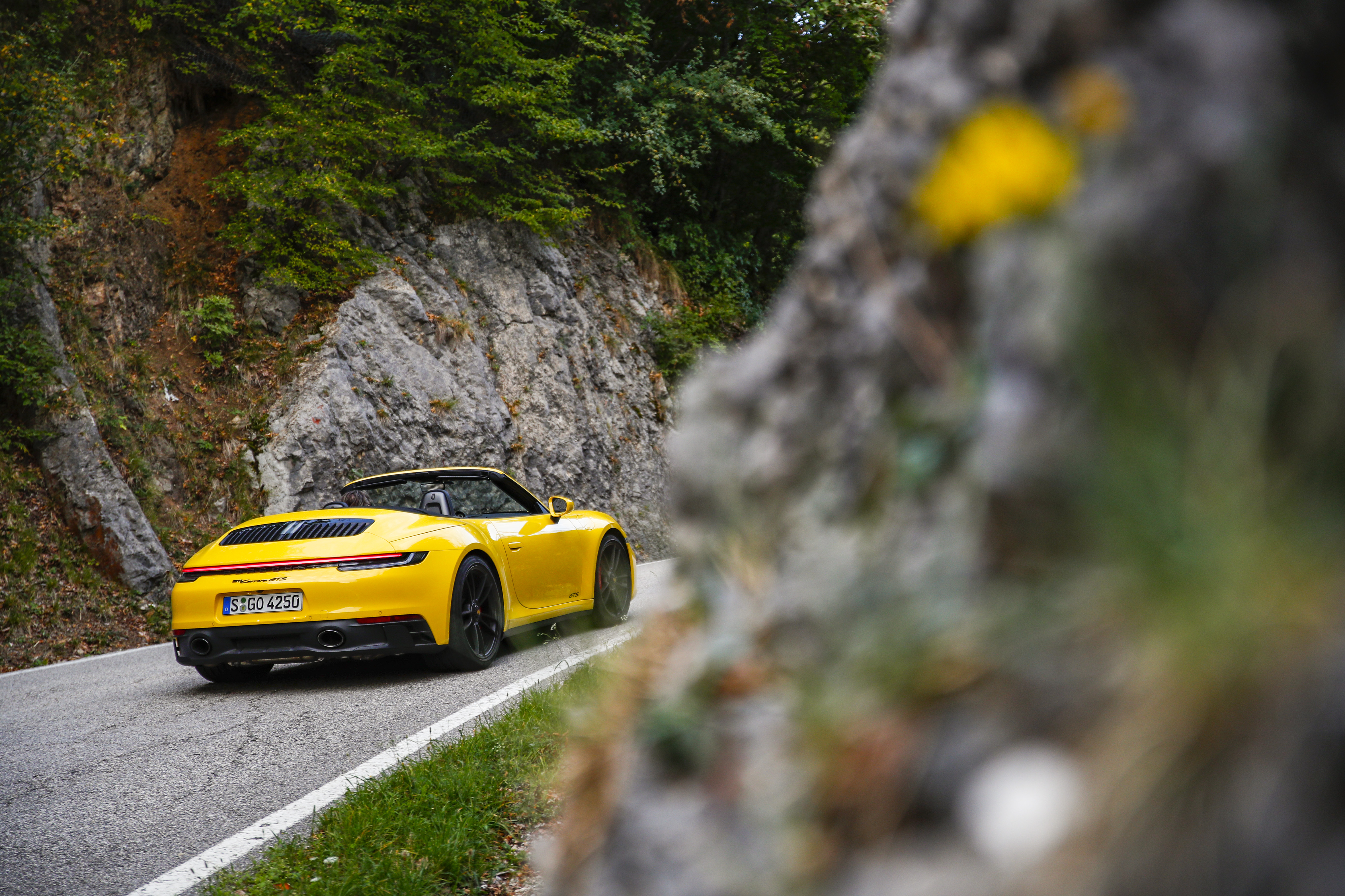 Yellow Porsche 911 Carrera GTS Cabriolet on mountain road HD Wallpaper