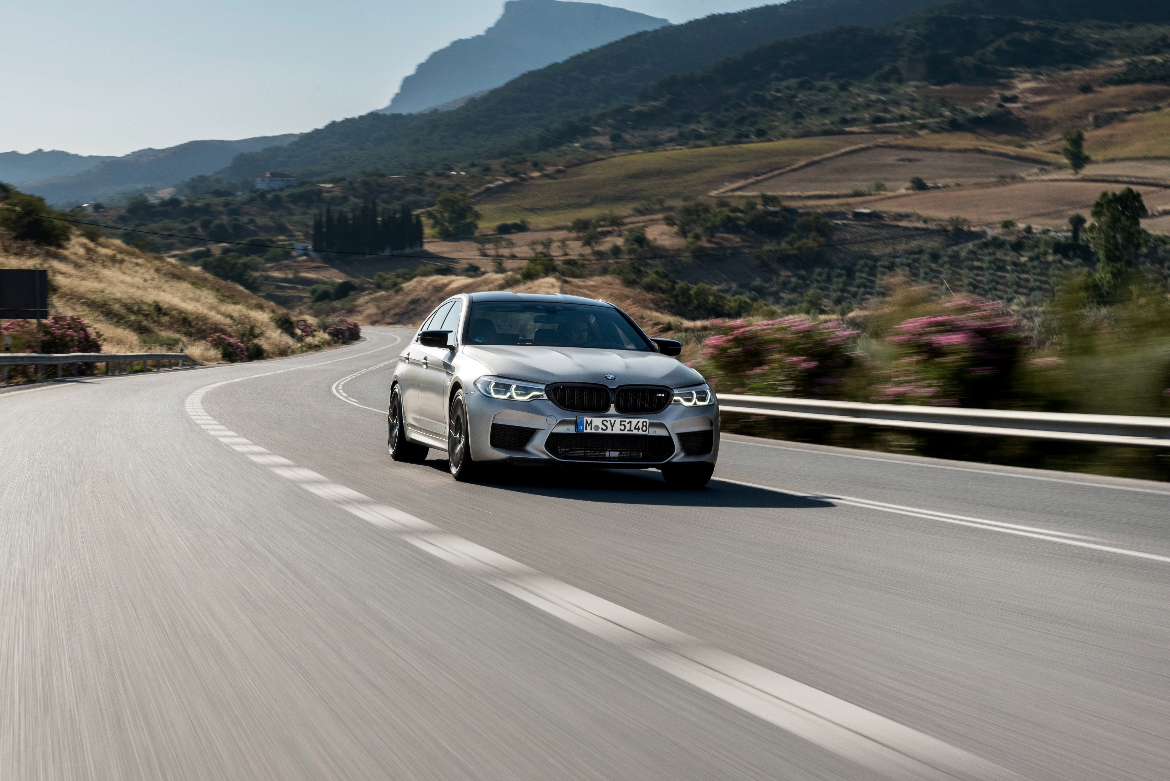 Luxury BMW M5 Competition driving on a winding road HD Wallpaper