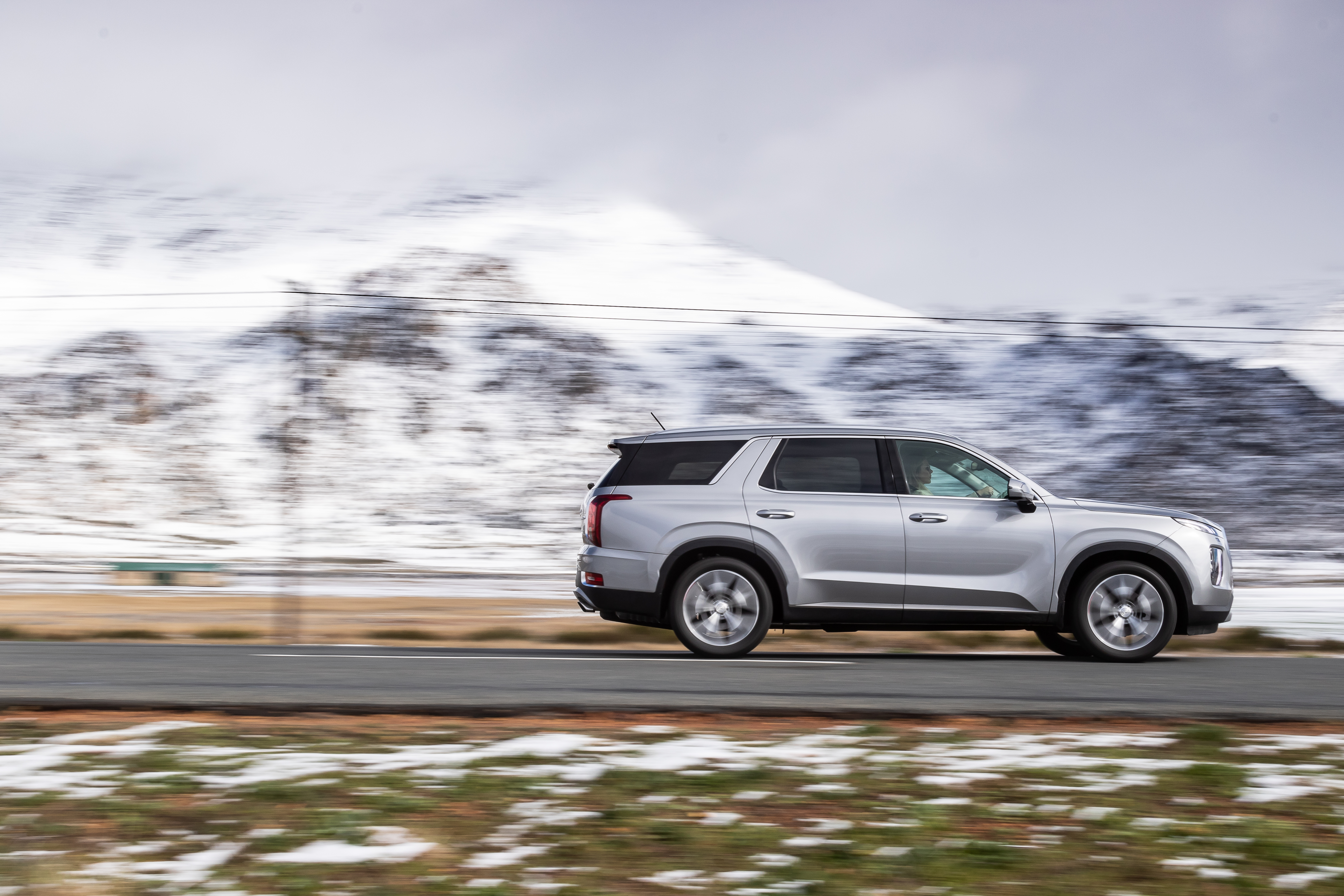 Hyundai Palisade SUV driving through snowy mountains HD Wallpaper