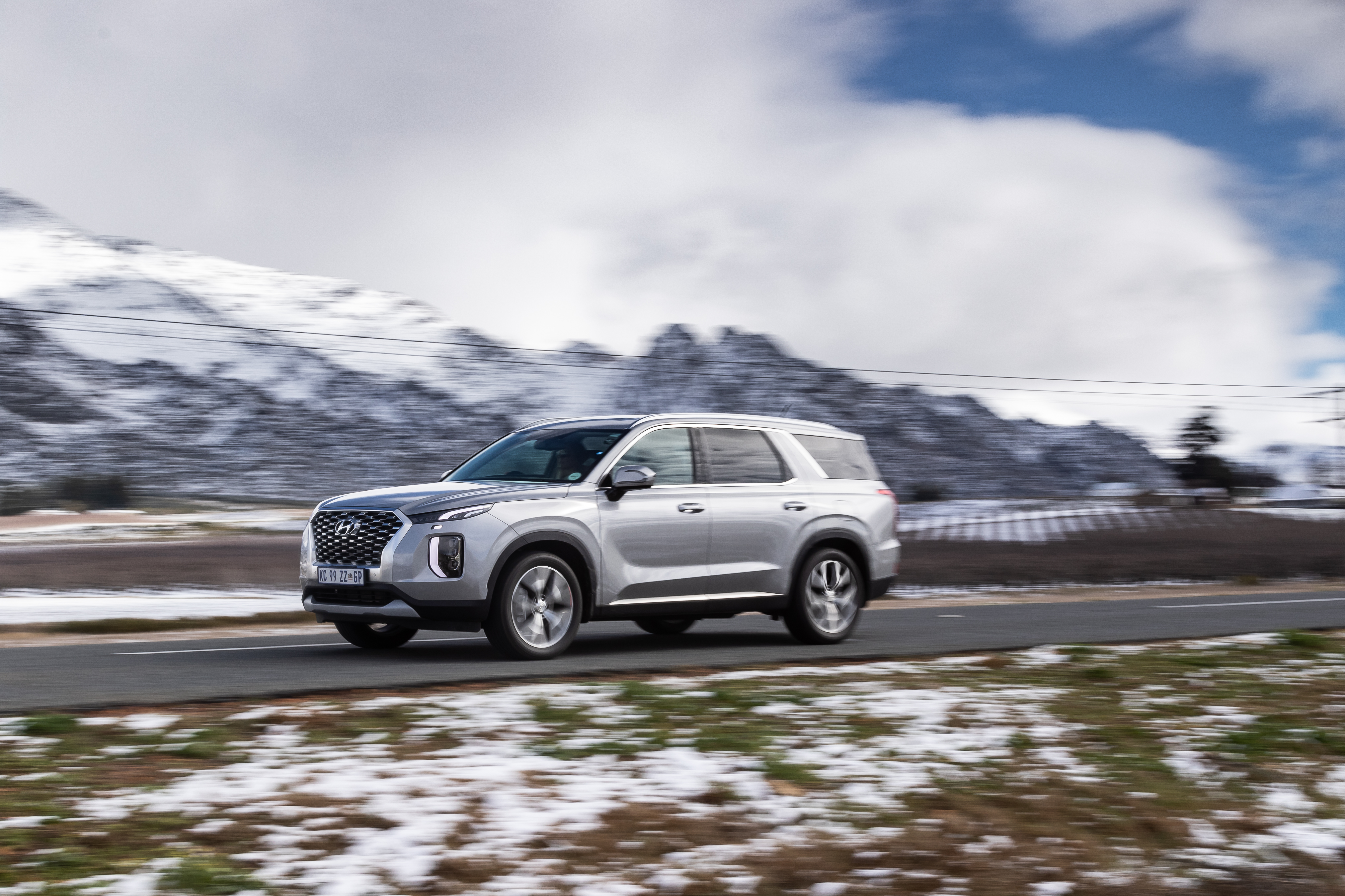 Hyundai Palisade SUV driving through snowy mountains HD Wallpaper