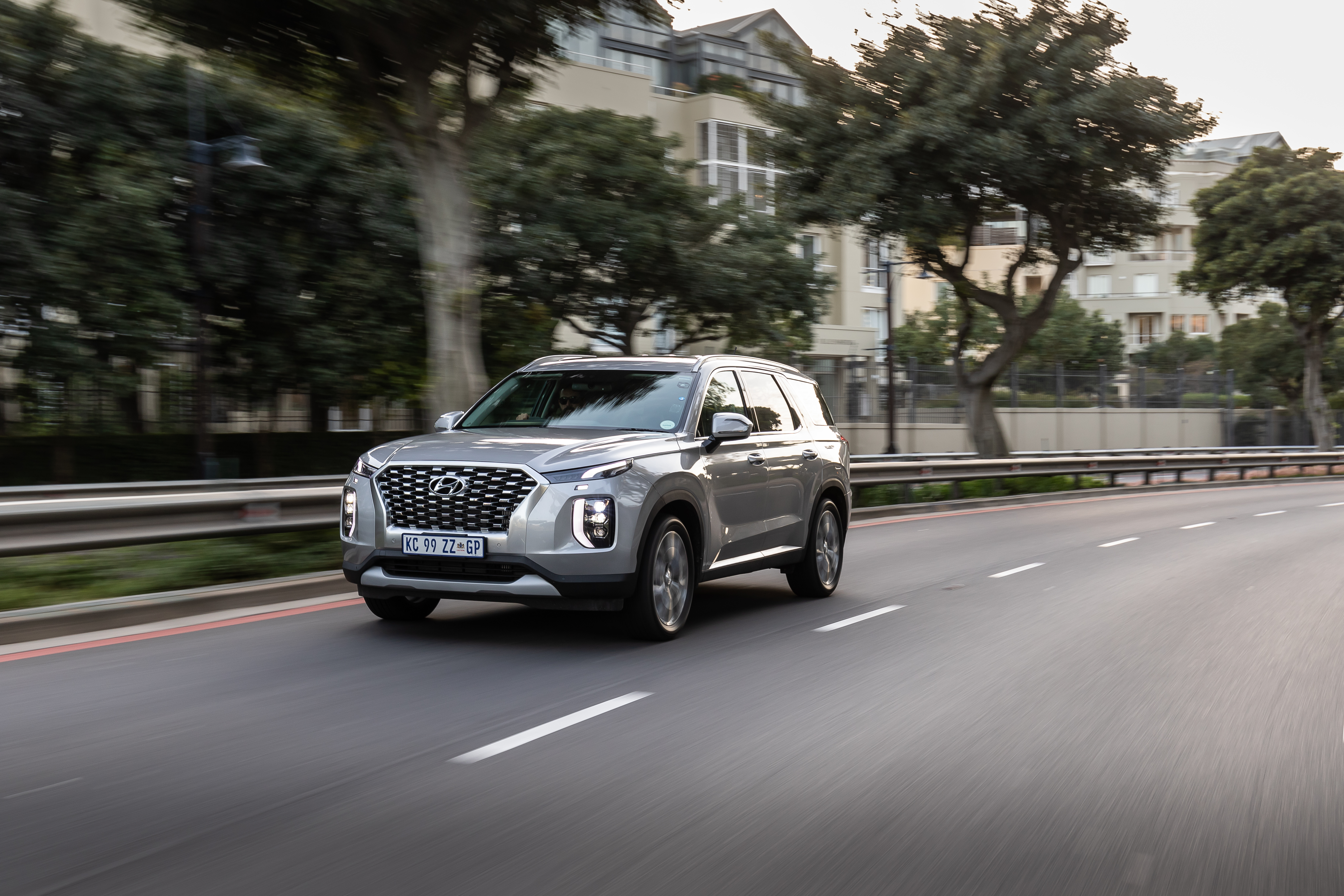 Silver Hyundai Palisade SUV driving on road HD Wallpaper