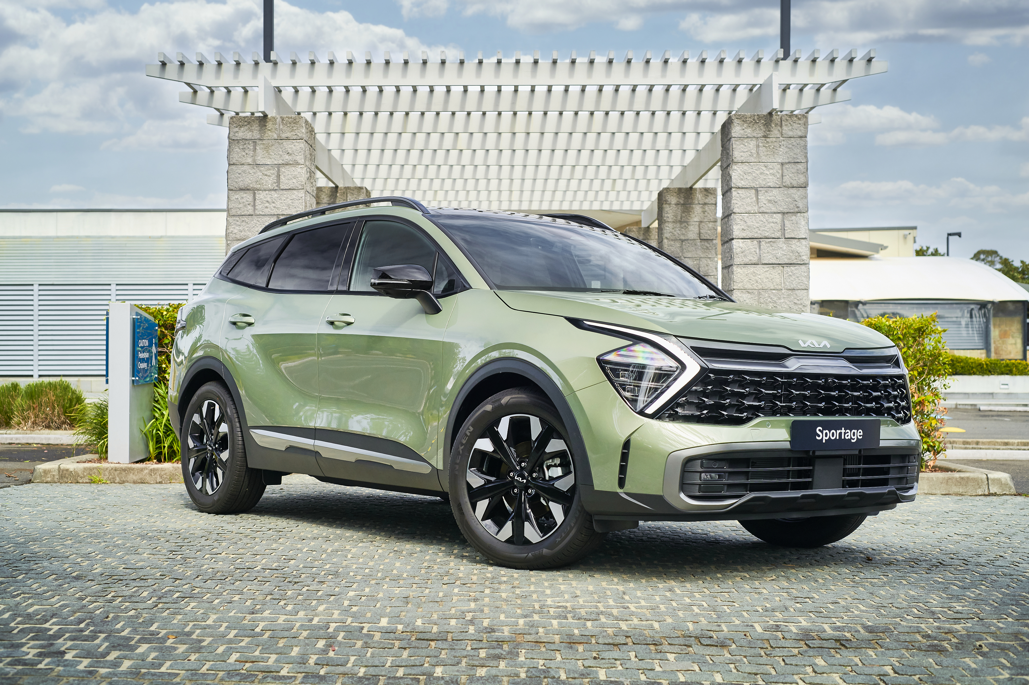 Green Kia Sportage SUV parked under a pergola HD Wallpaper