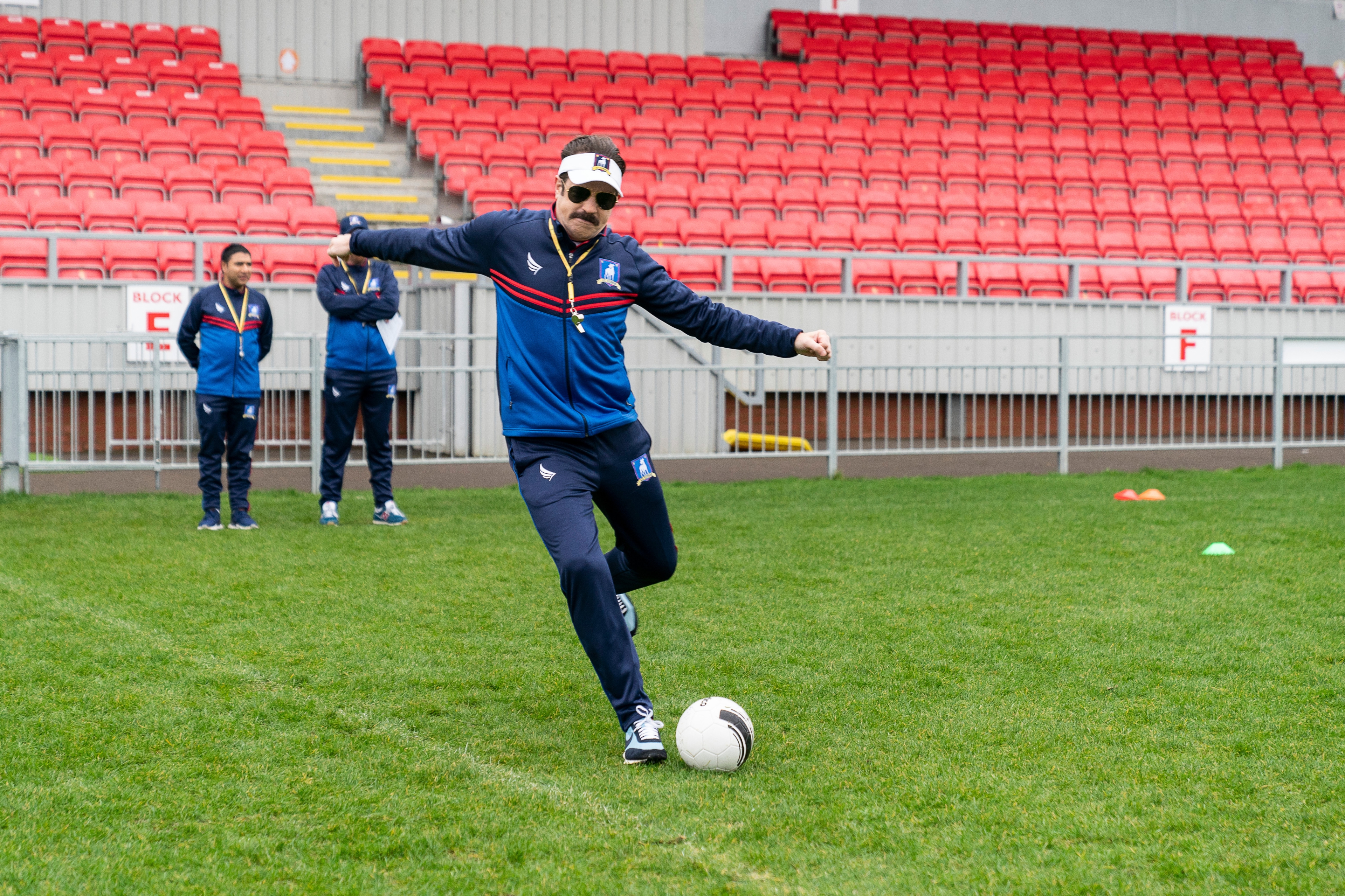 Ted Lasso kicking soccer ball on field HD Wallpaper