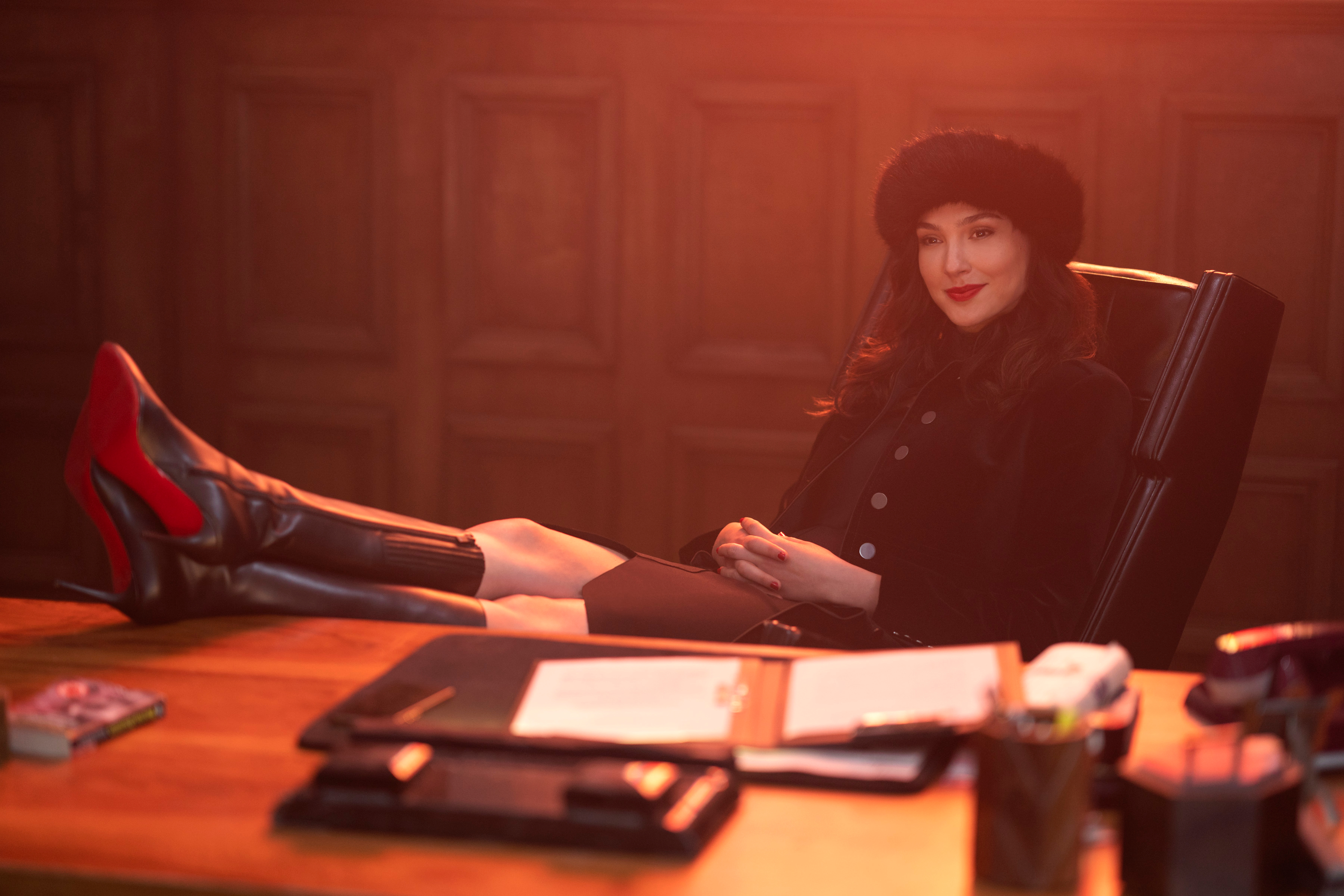 Gal Gadot in fur hat with boots on office desk HD Wallpaper