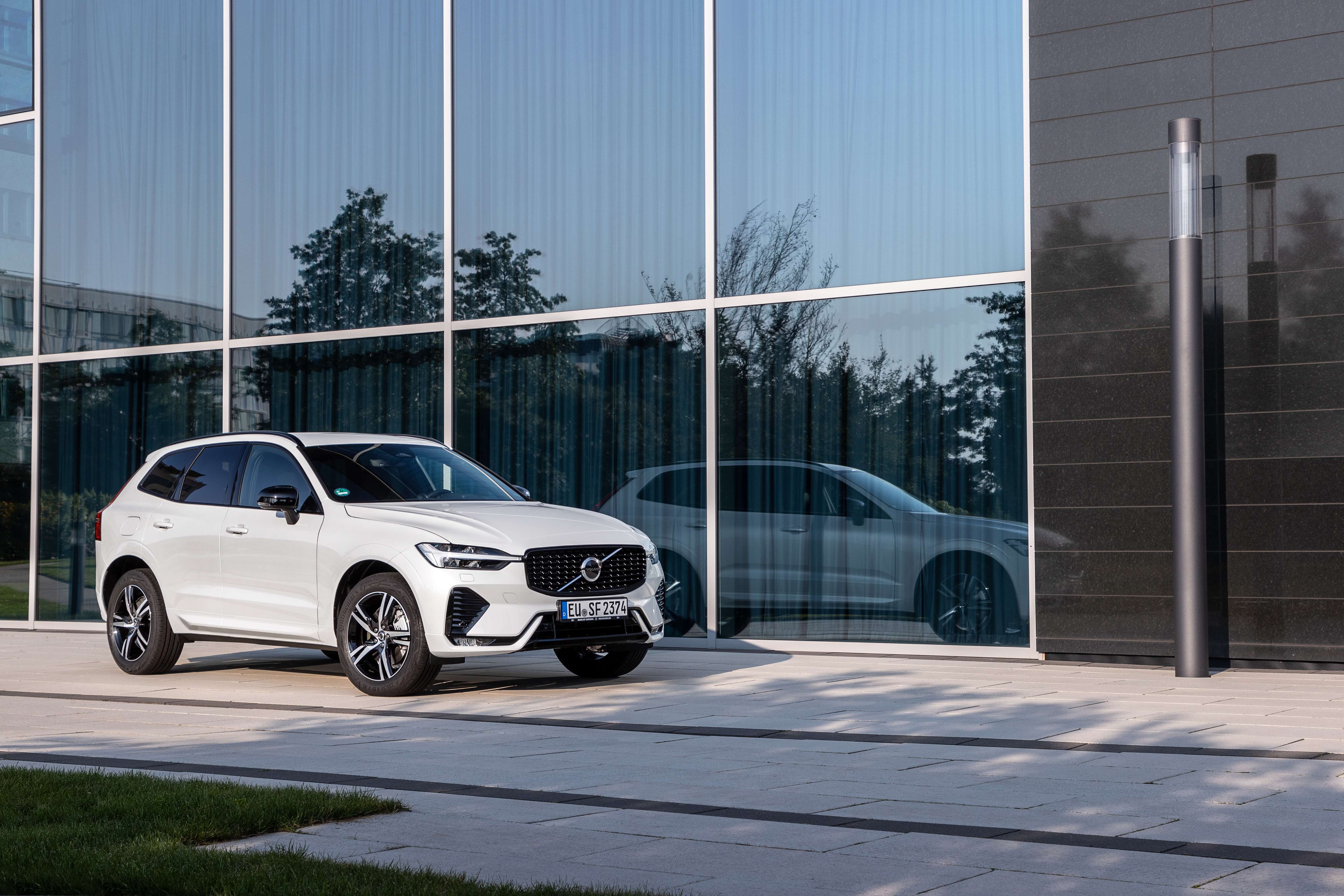 White Volvo XC60 B5 R-Design SUV at modern building HD Wallpaper