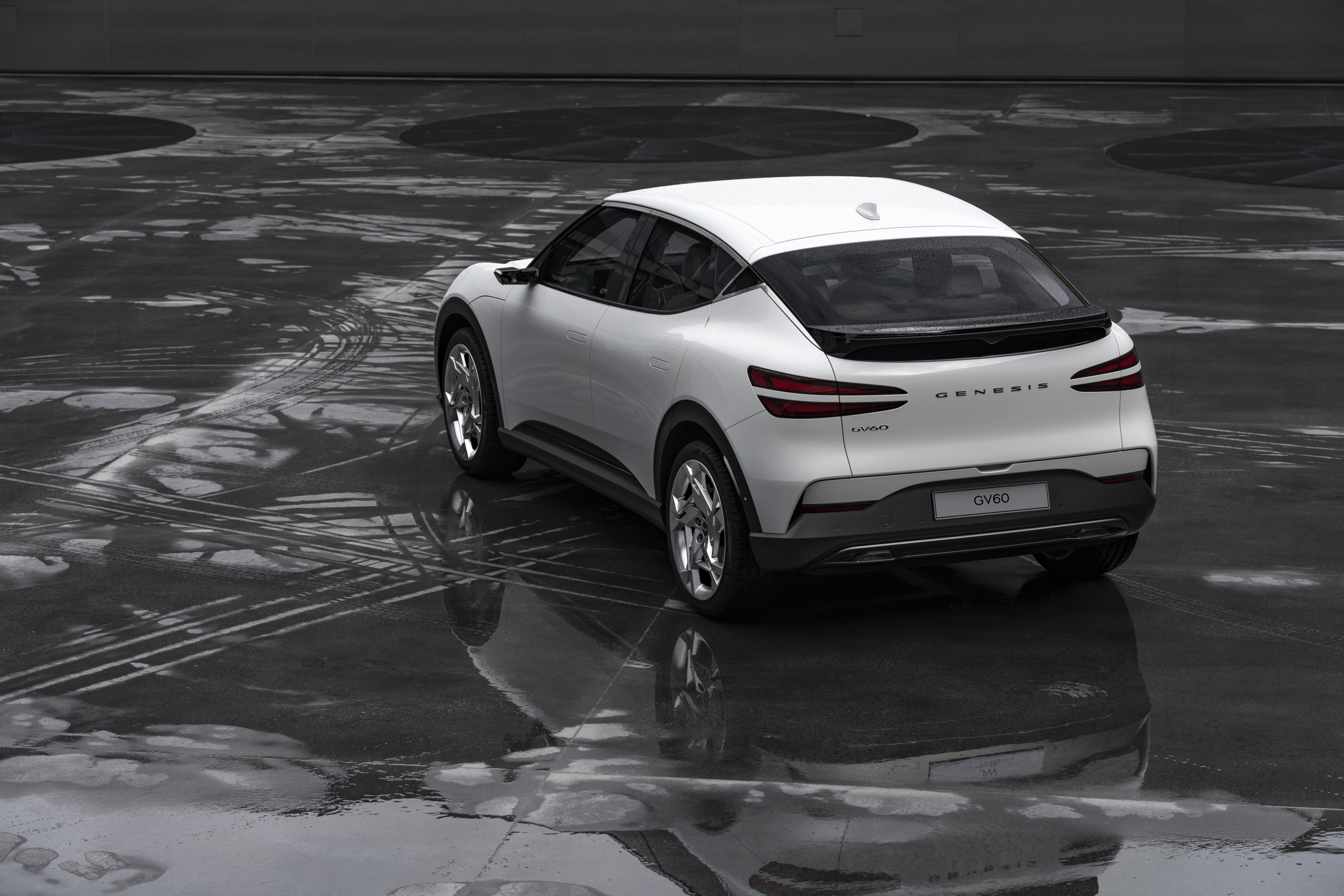 White Genesis GV60 SUV on wet pavement HD Wallpaper