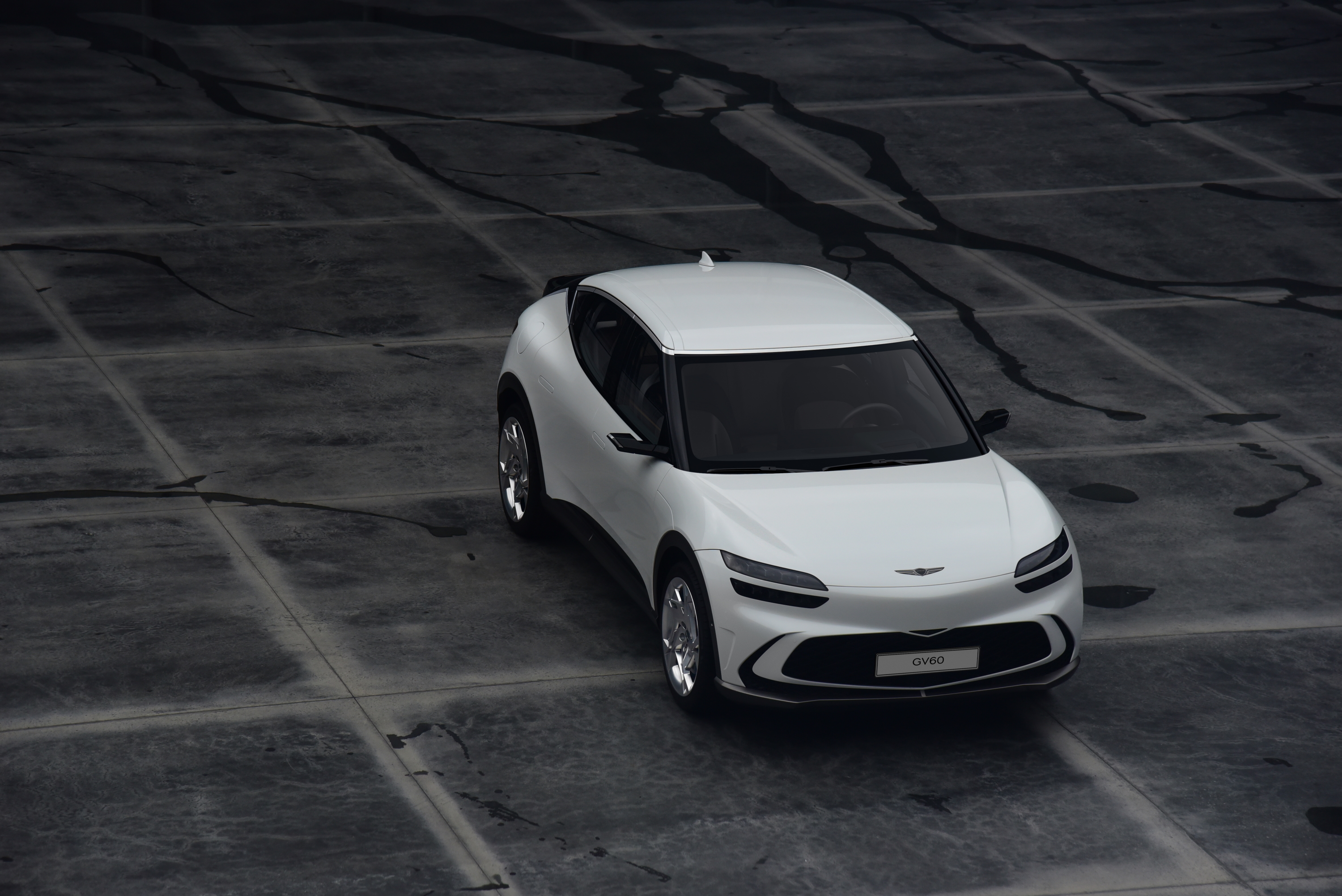 White Genesis GV60 SUV on dark textured ground HD Wallpaper