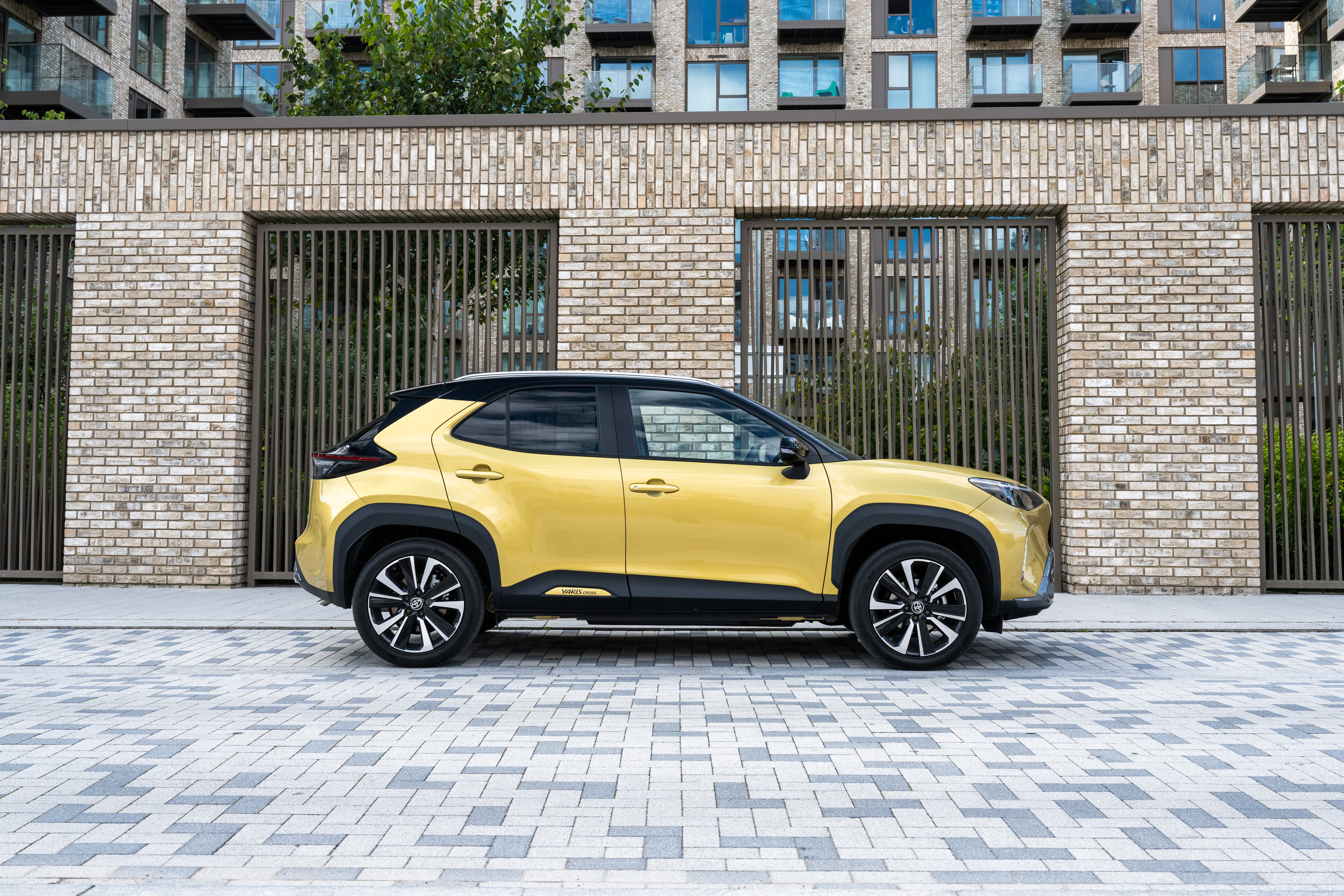 Yellow Toyota Yaris Cross Hybrid SUV by brick building HD Wallpaper