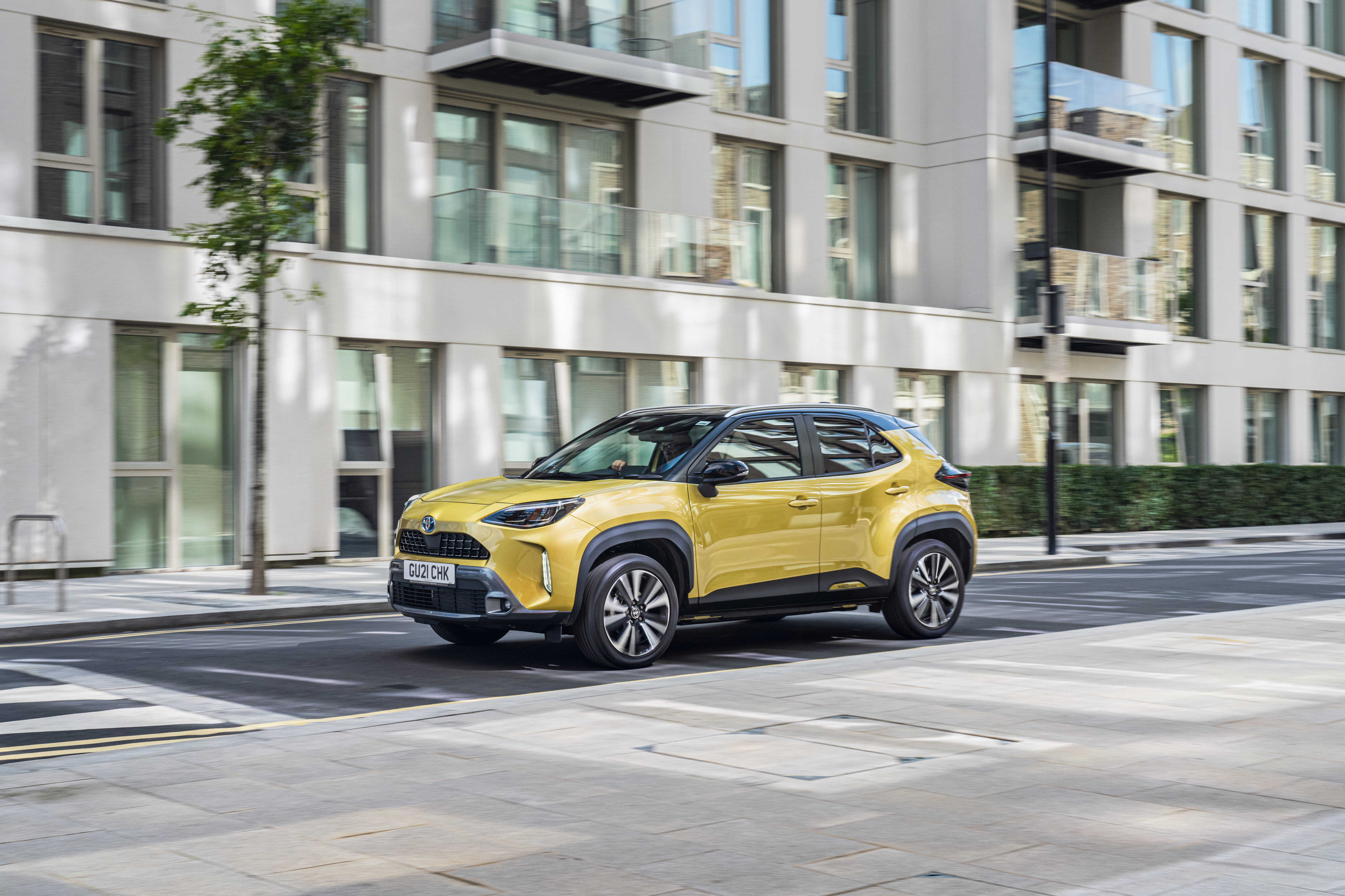 Yellow Toyota Yaris Cross Hybrid SUV on city street HD Wallpaper