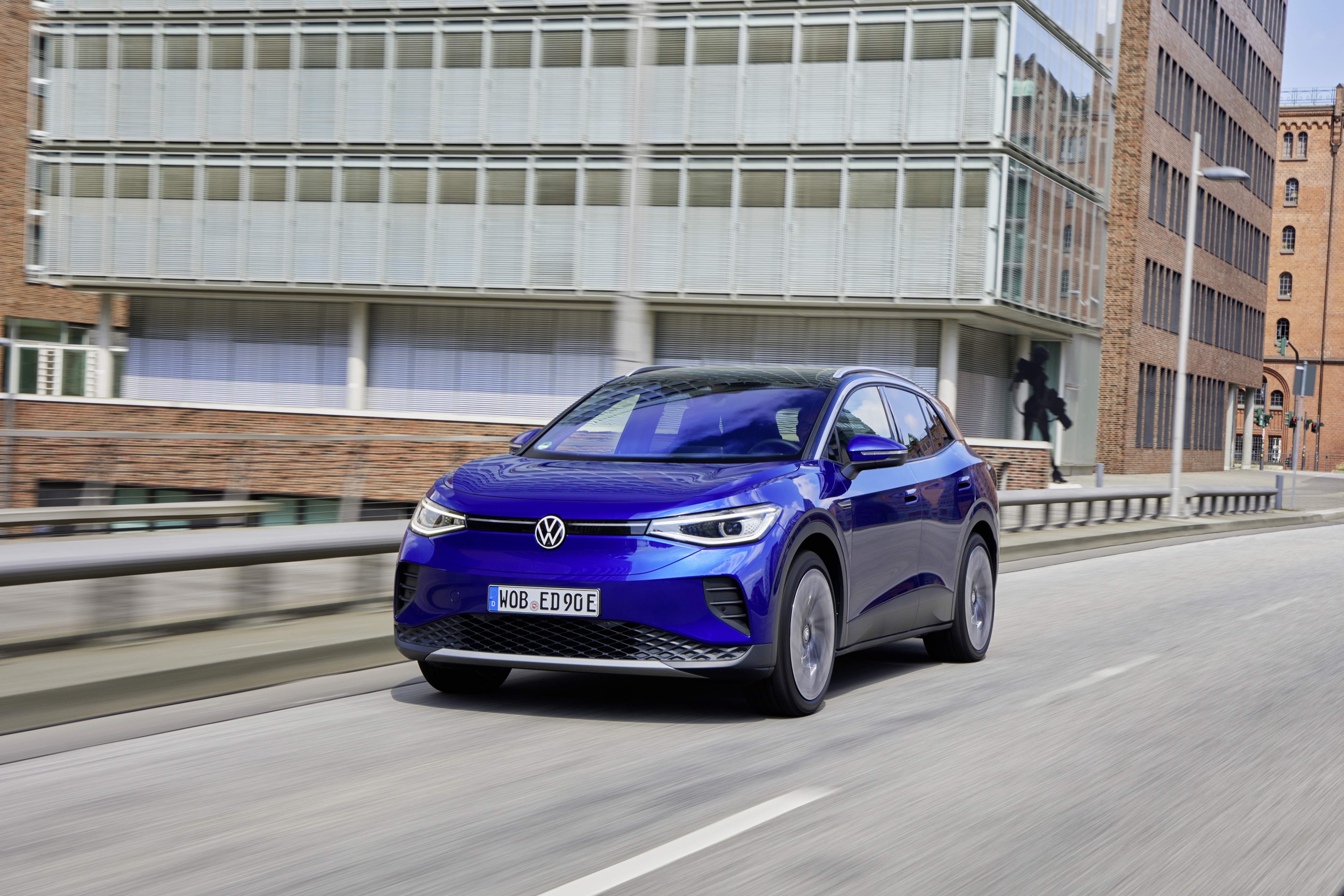 Blue Volkswagen ID.4 electric car driving in city HD Wallpaper