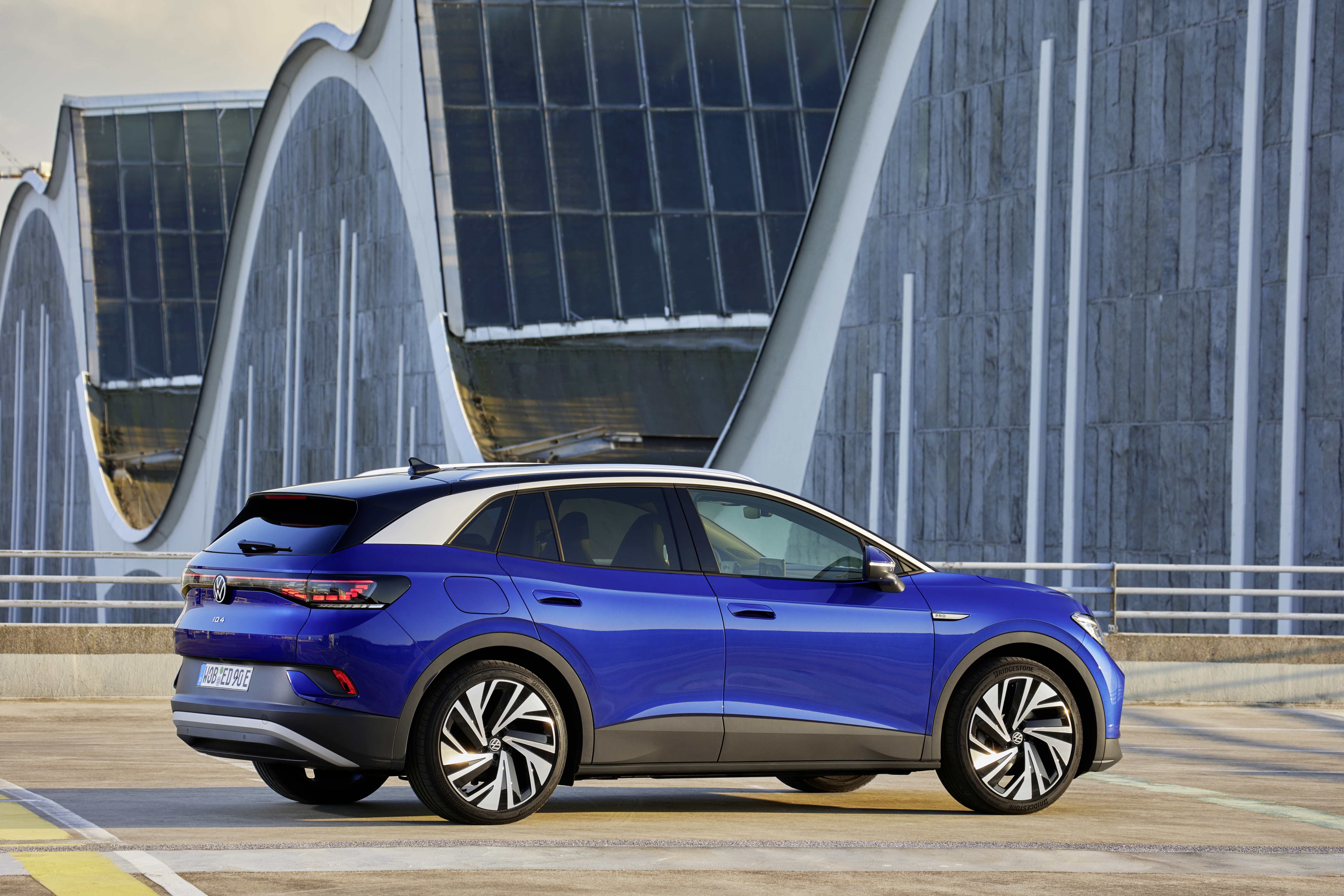 Blue Volkswagen ID.4 Pro Electric Car with Modern Building HD Wallpaper