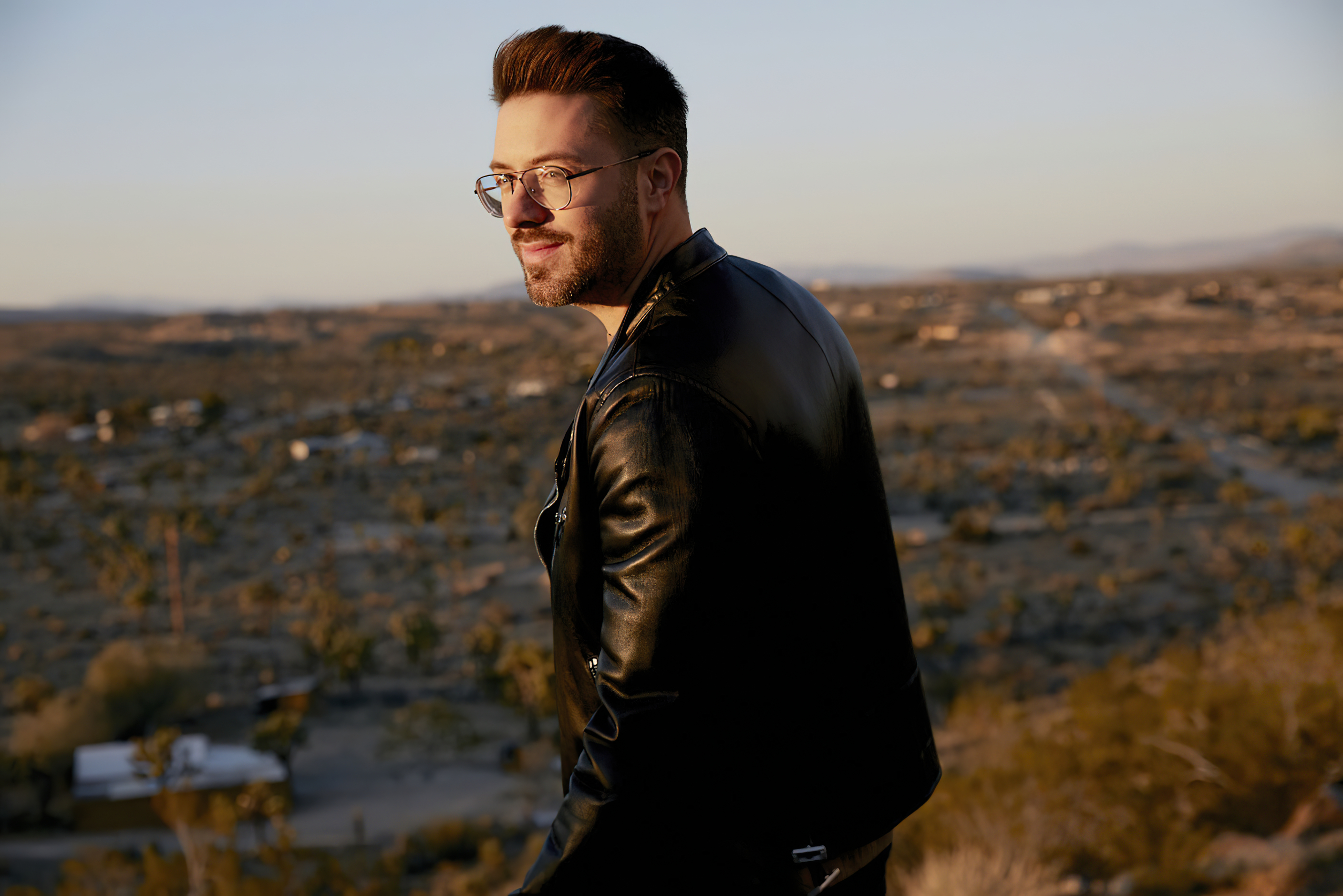 Danny Gokey in leather jacket overlooking desert landscape HD Wallpaper