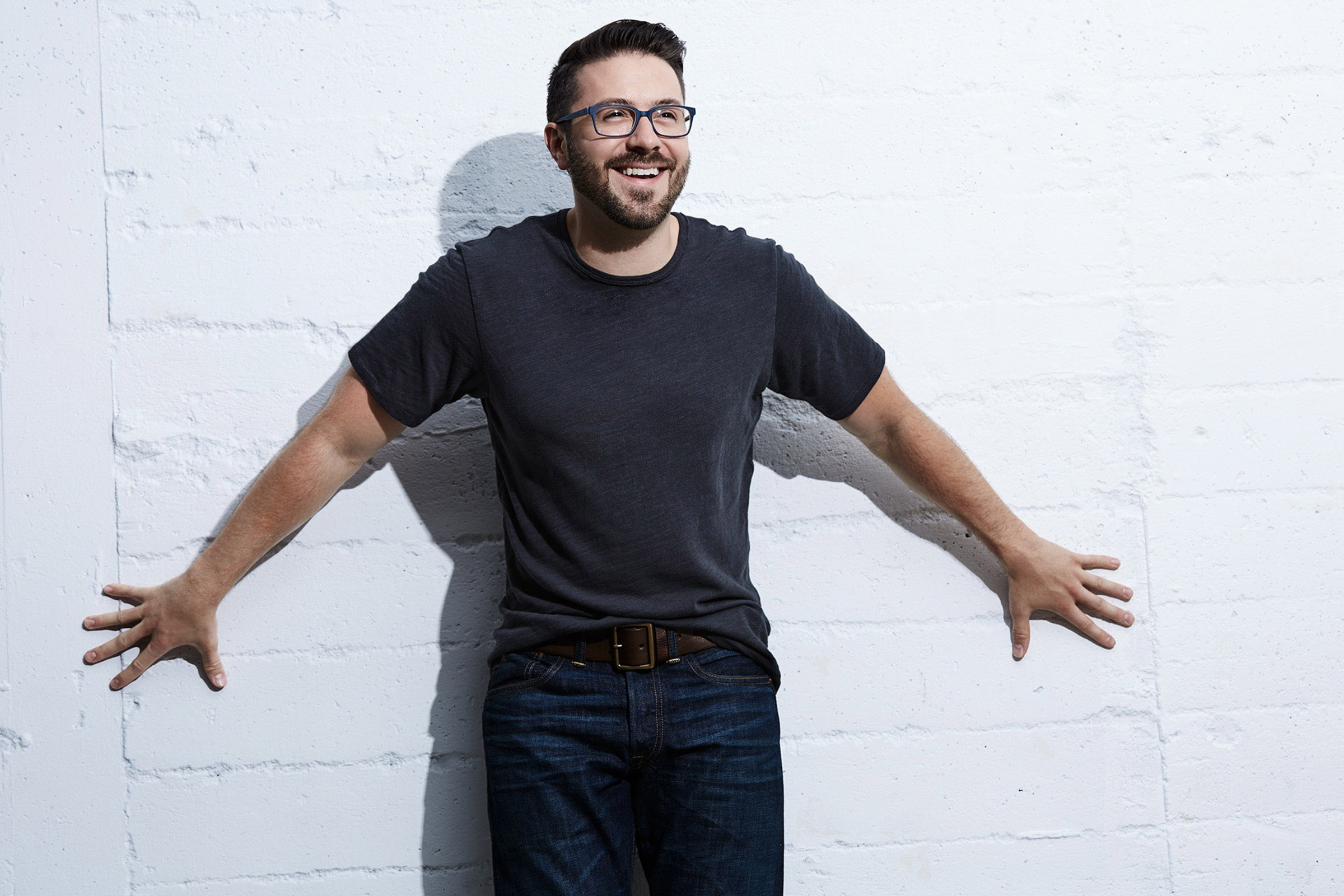 Danny Gokey smiling against a white brick wall HD Wallpaper