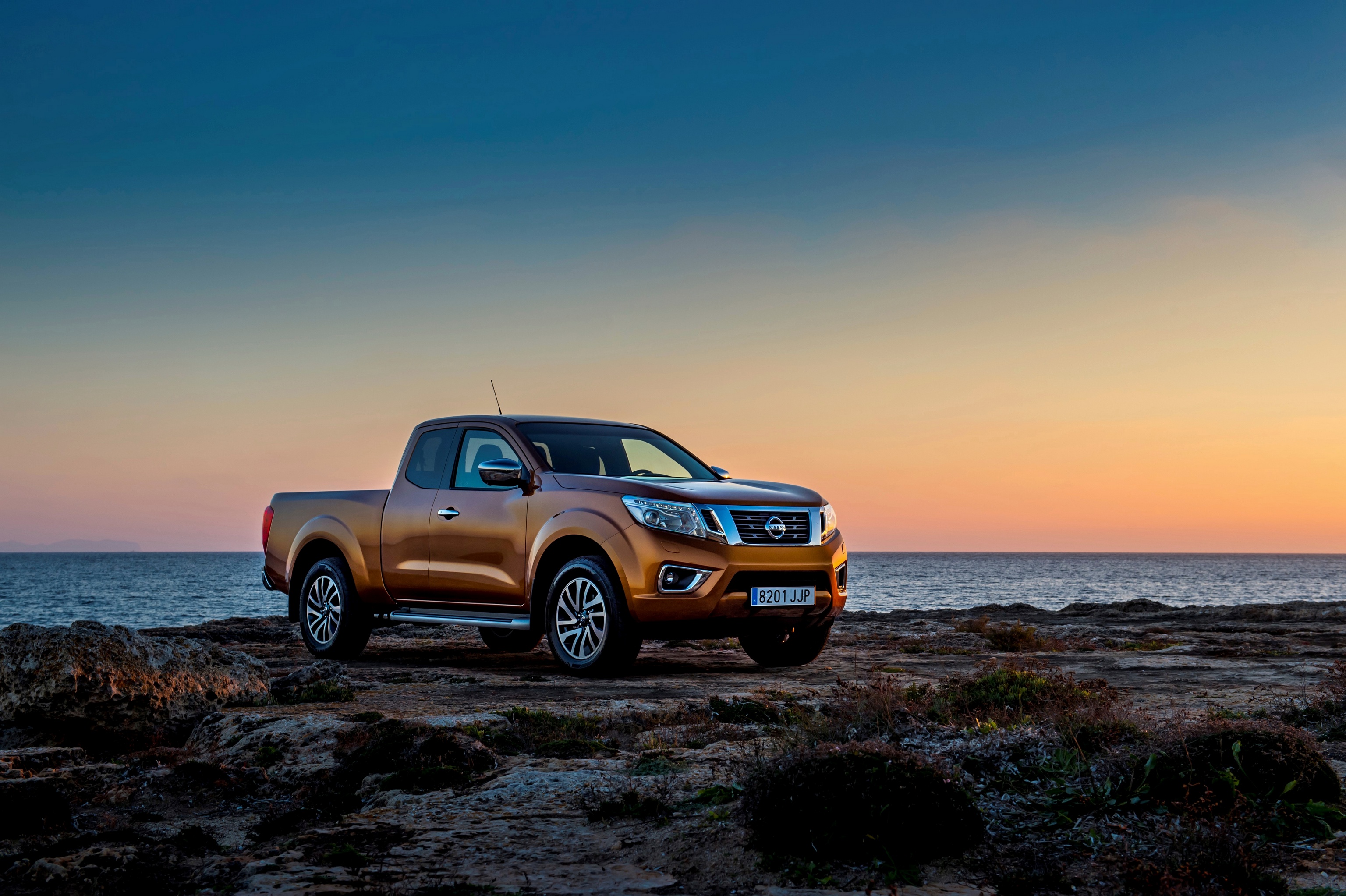 Nissan Navara pickup on rocky shore at sunset HD Wallpaper