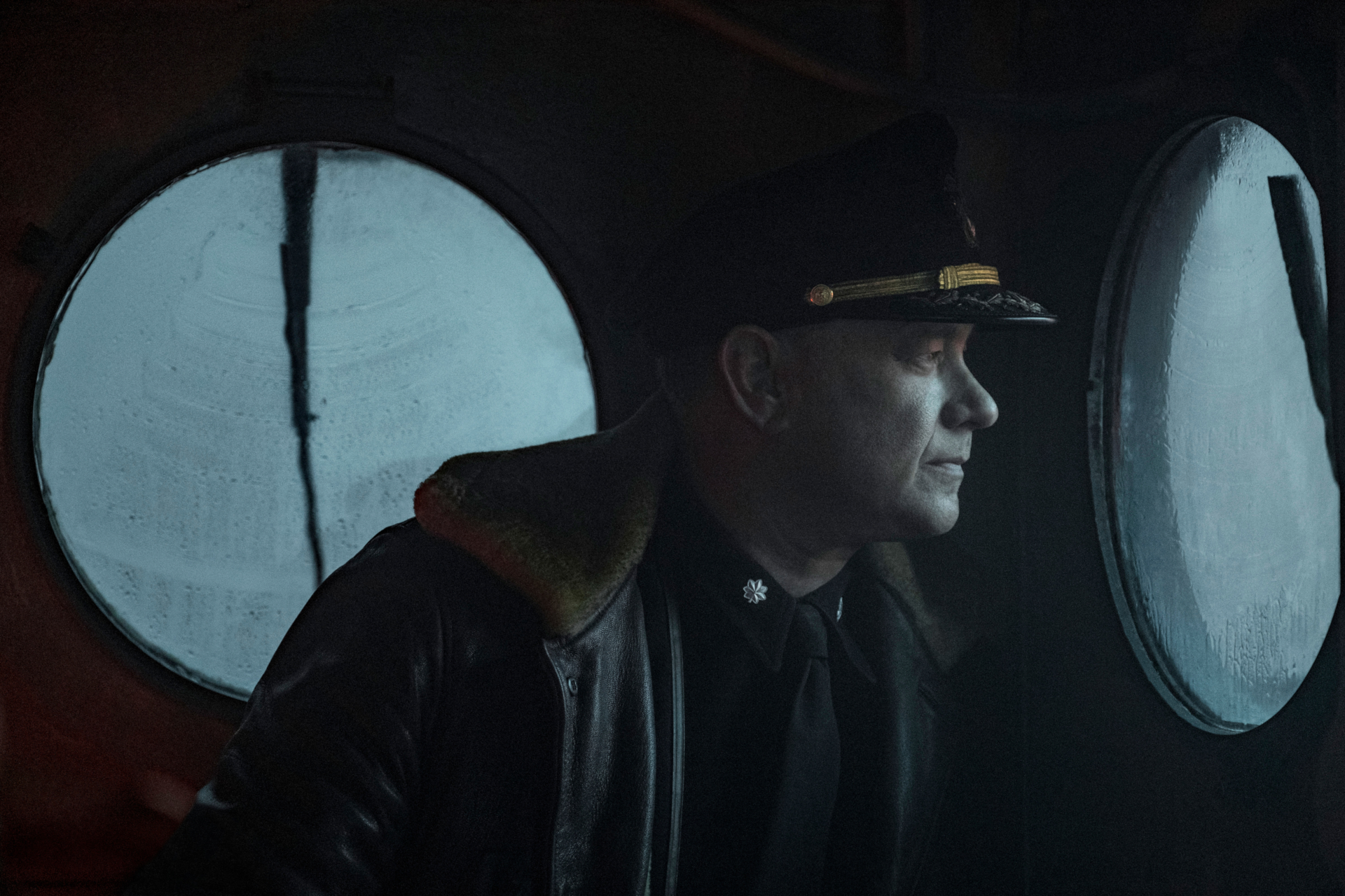Tom Hanks as Captain Krause looking out porthole in Greyhound HD Wallpaper