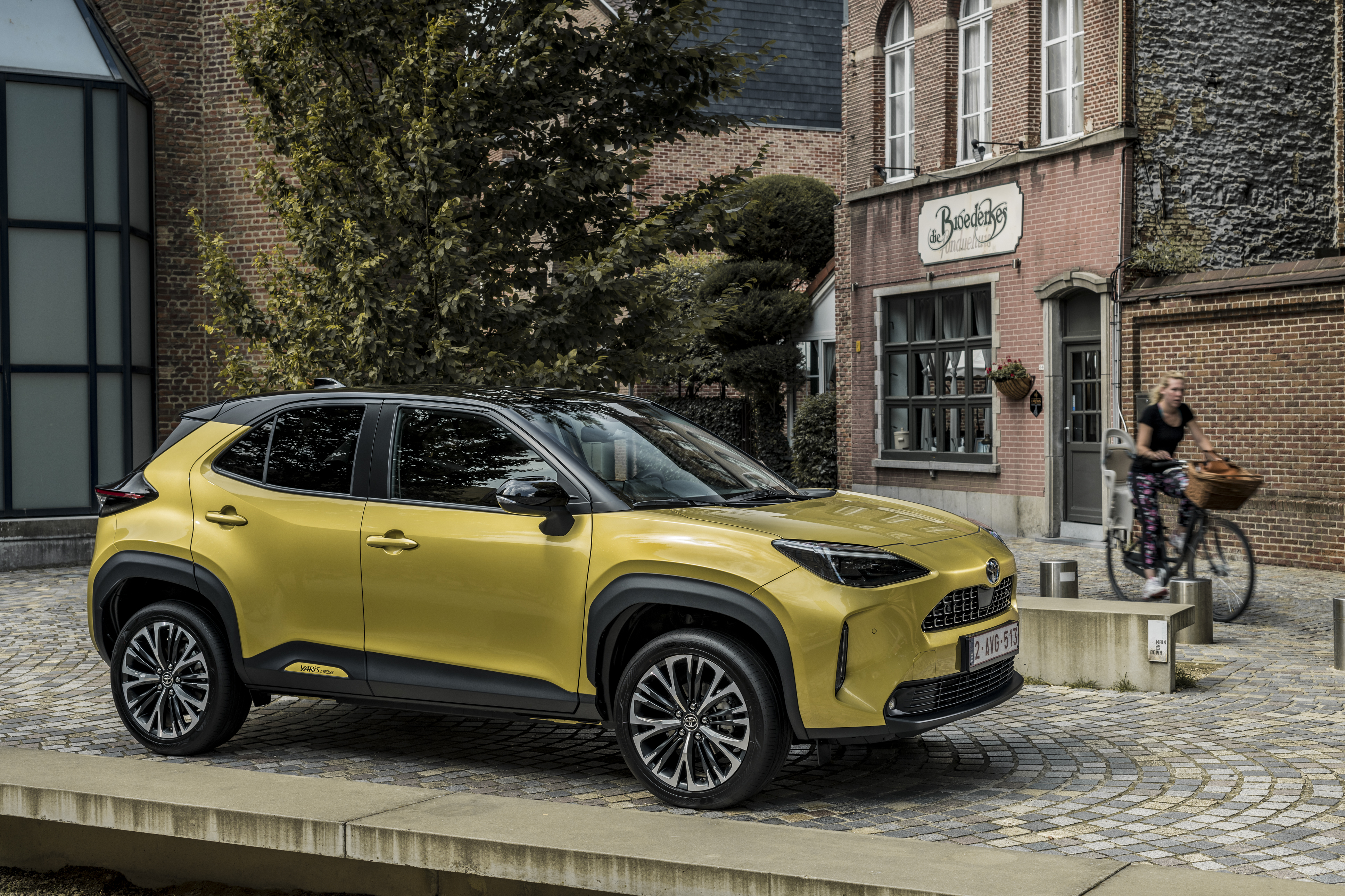 Yellow Toyota Yaris Cross Hybrid SUV on cobblestone street HD Wallpaper