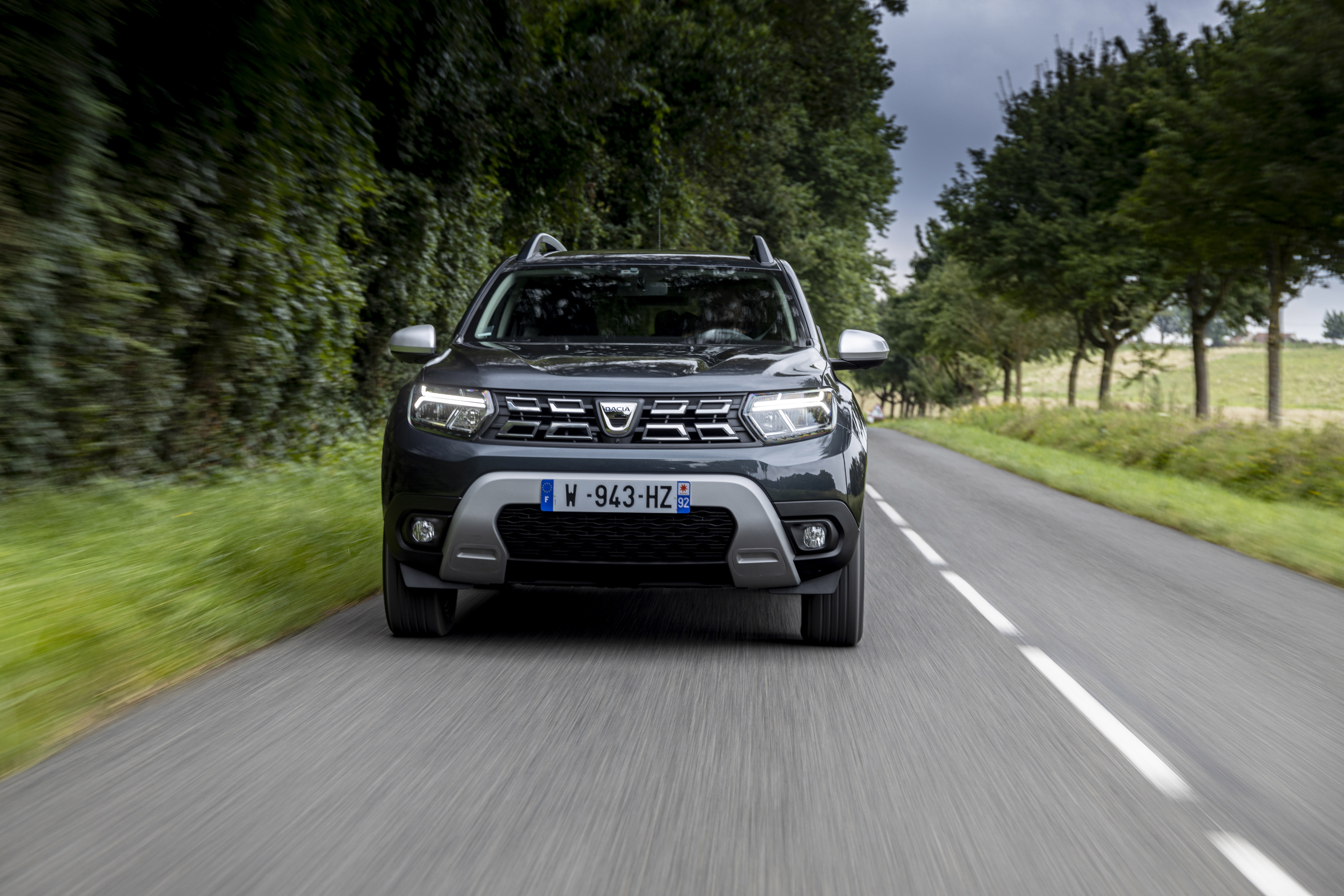 Dacia Duster SUV on a tree-lined road HD Wallpaper