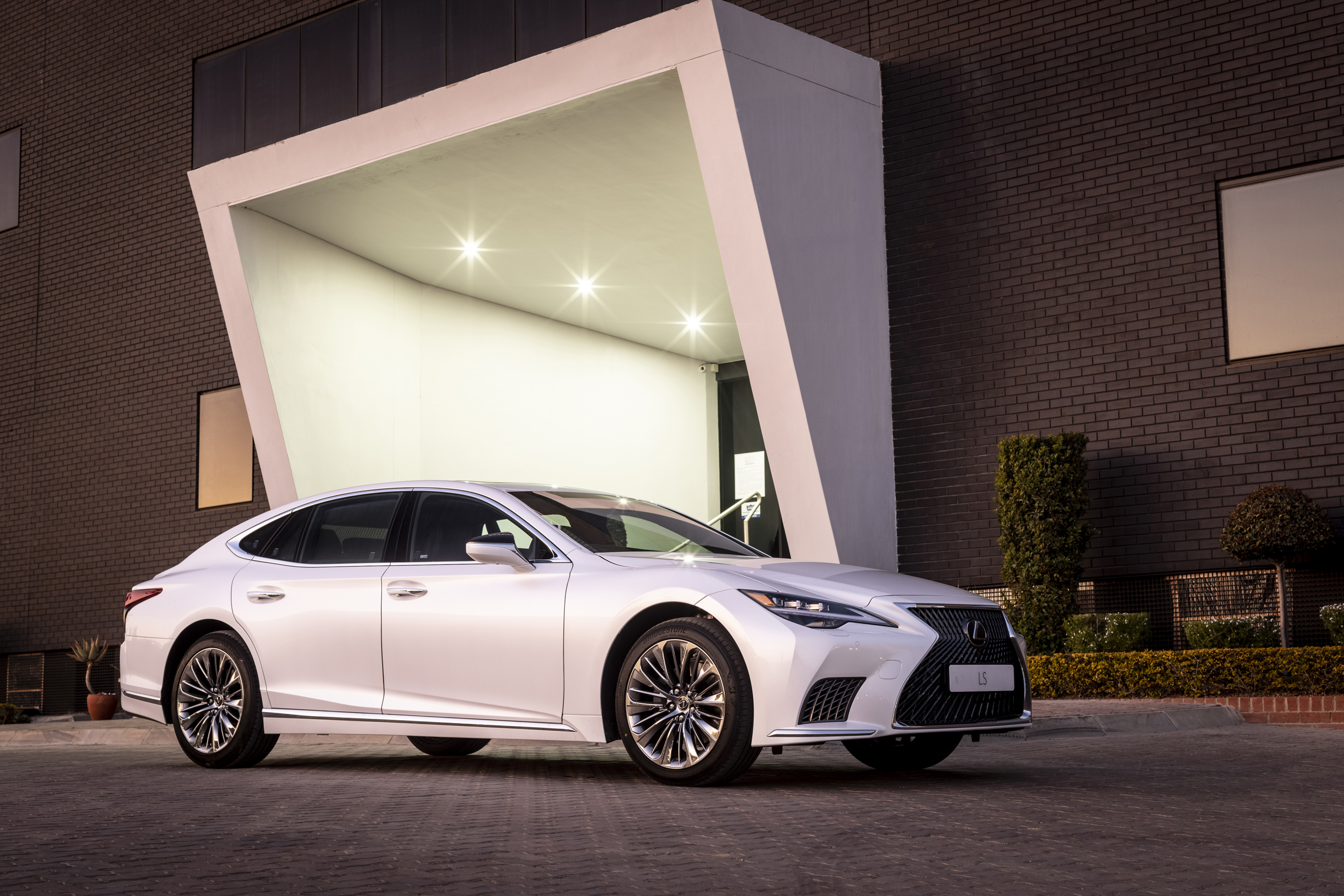 White Lexus LS 500 luxury car at modern building entrance HD Wallpaper