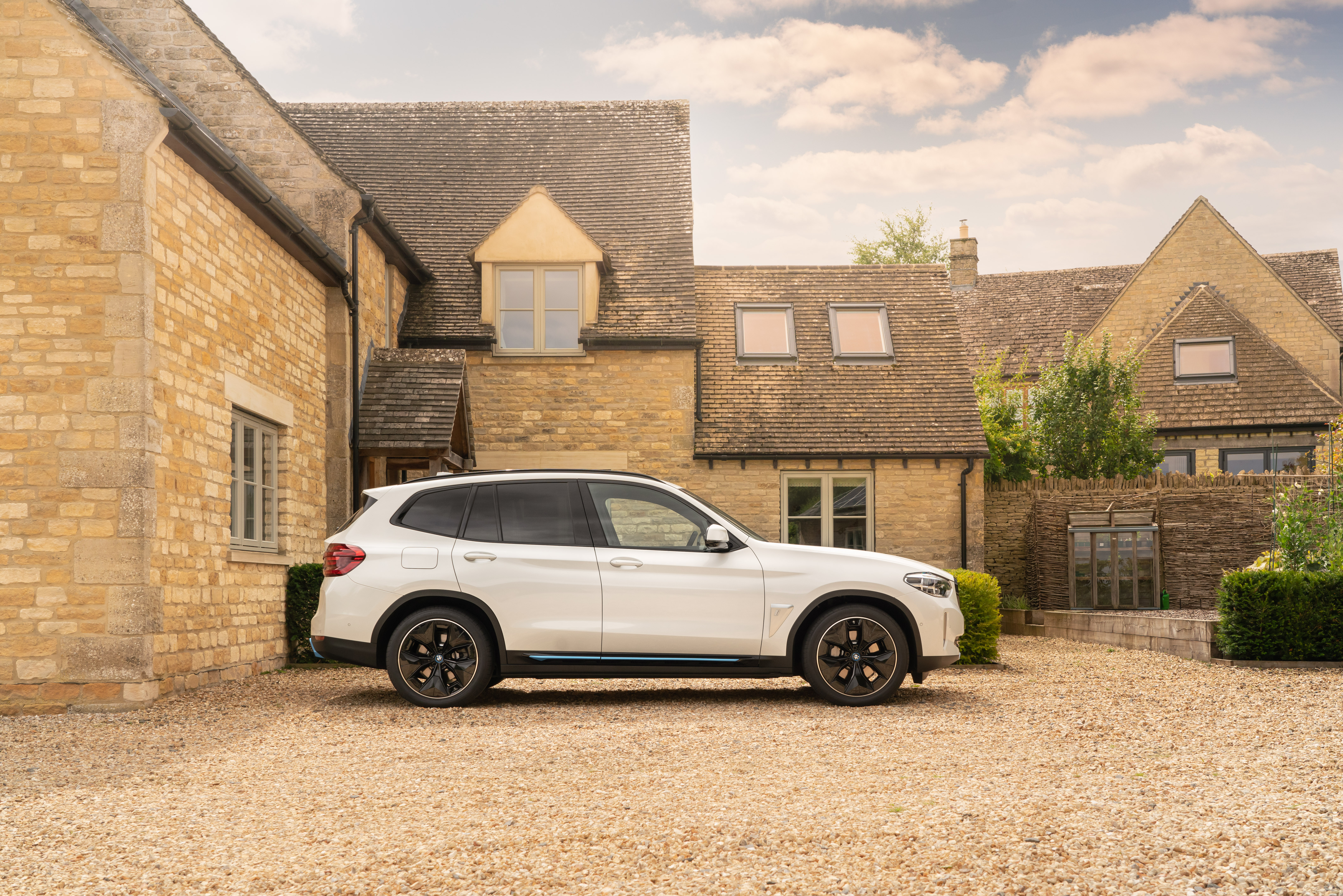 White BMW iX3 electric SUV parked at a stone house HD Wallpaper