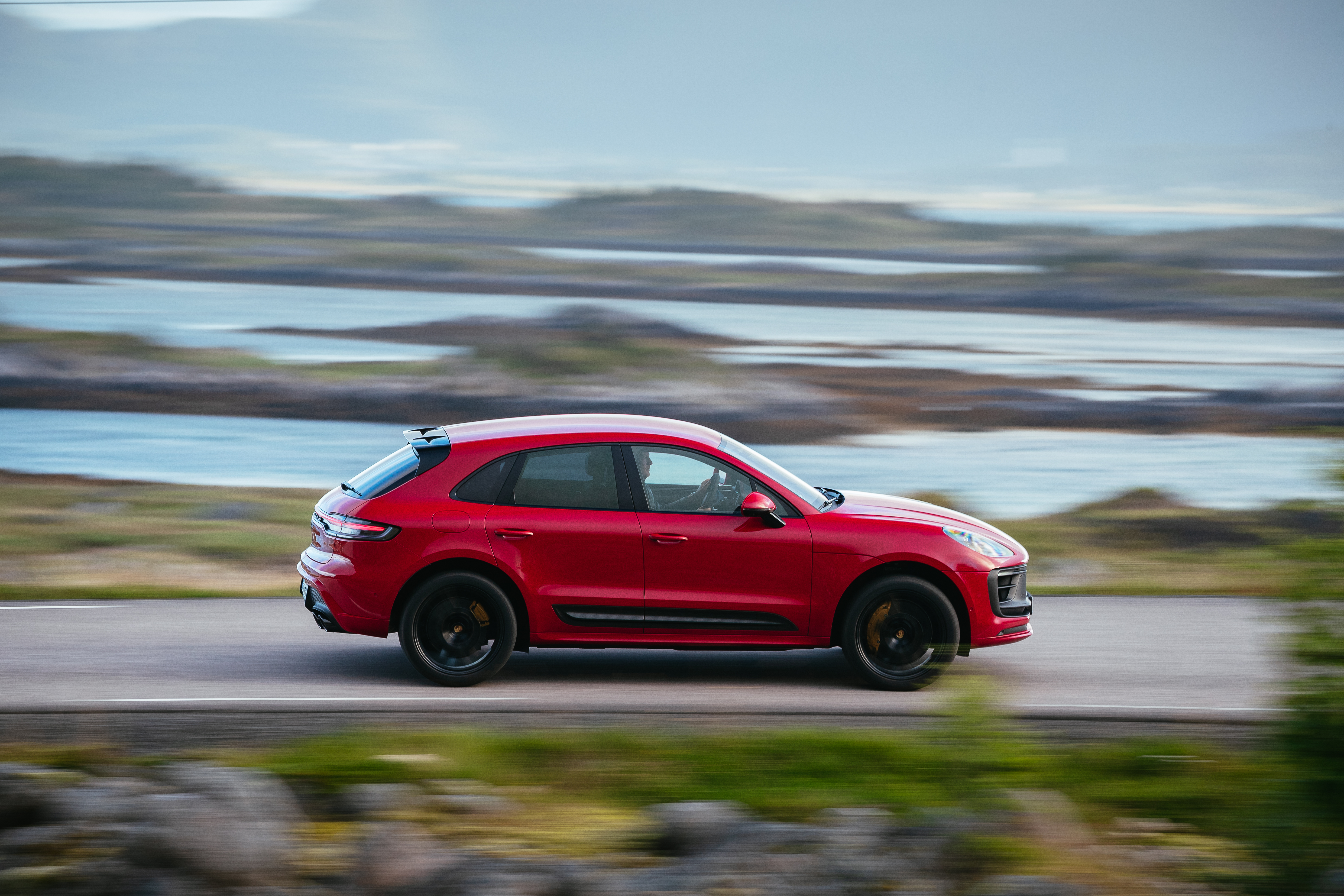Red Porsche Macan GTS SUV driving on a scenic road HD Wallpaper