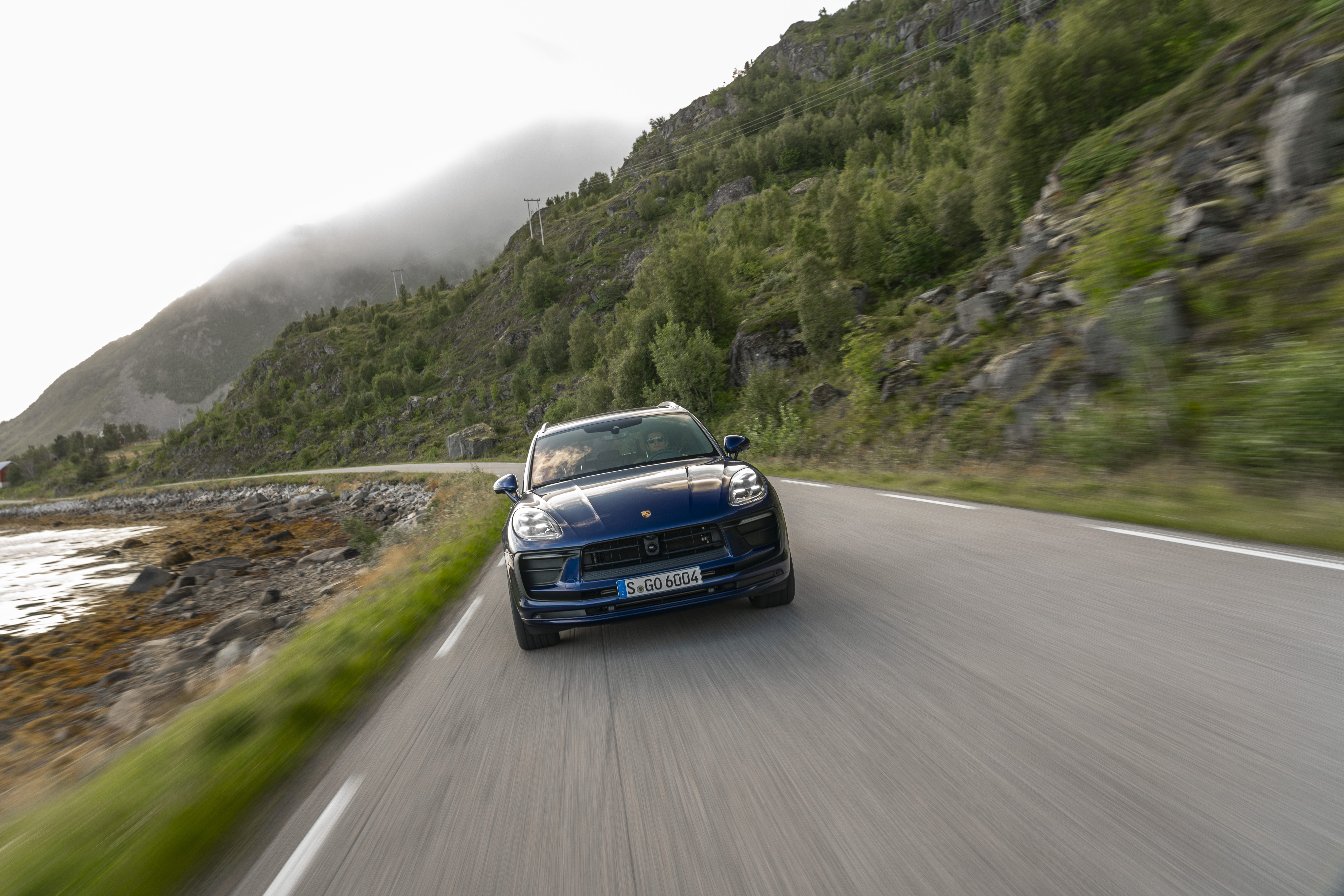 Blue Porsche Macan SUV driving on a scenic mountain road HD Wallpaper