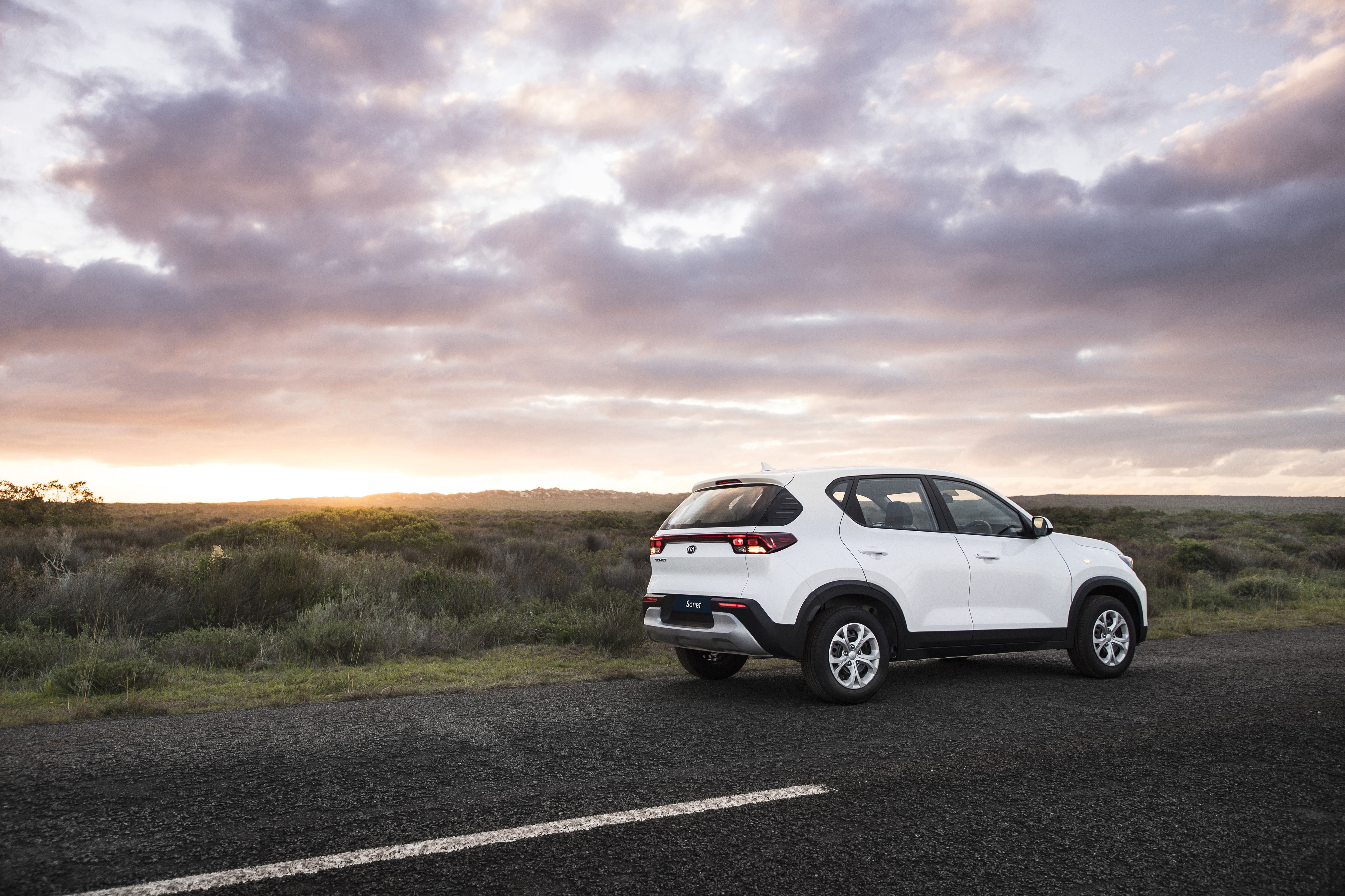 White Kia Sonet SUV on road at sunset HD Wallpaper