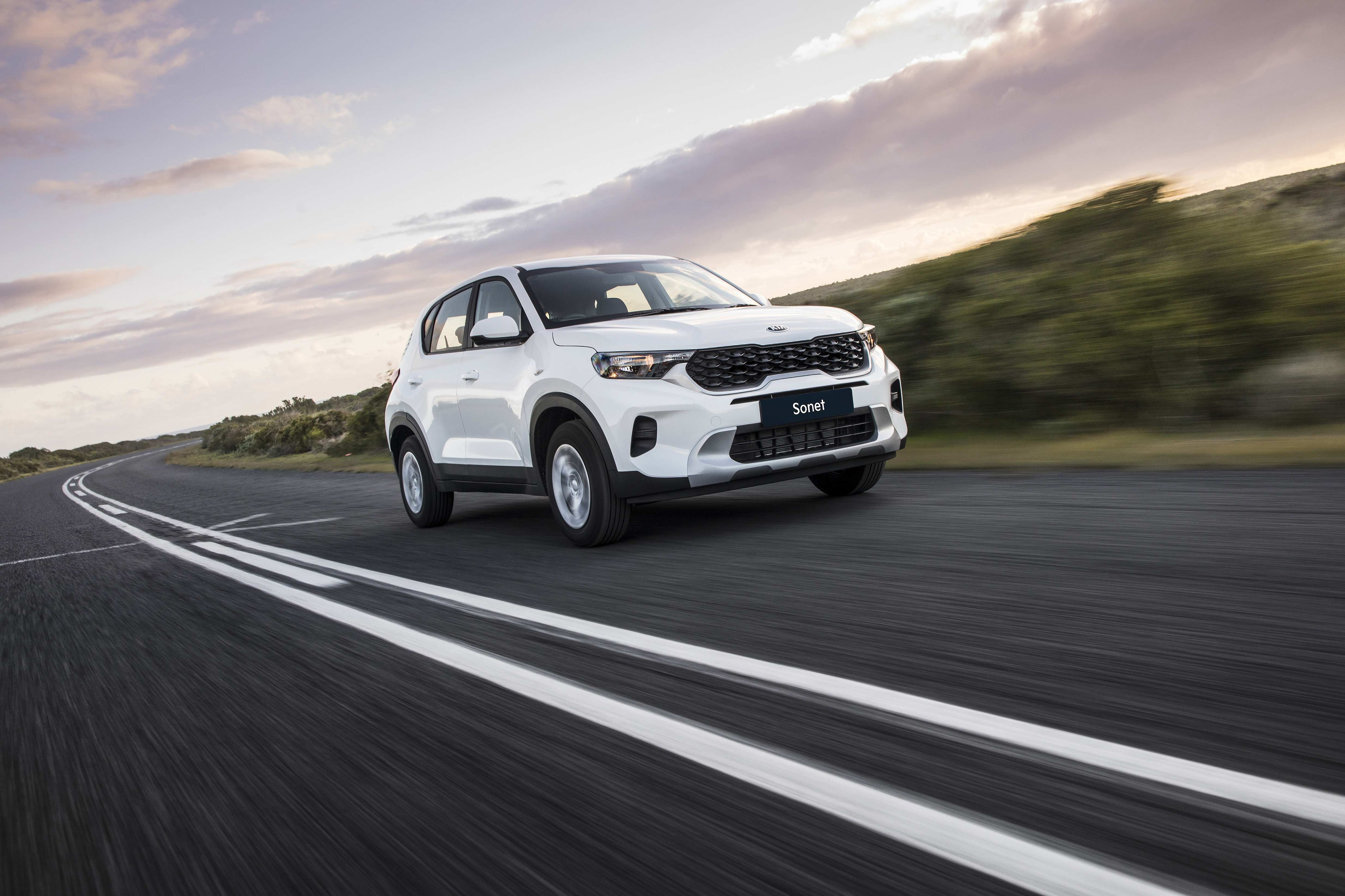 White Kia Sonet LX SUV driving on a road HD Wallpaper