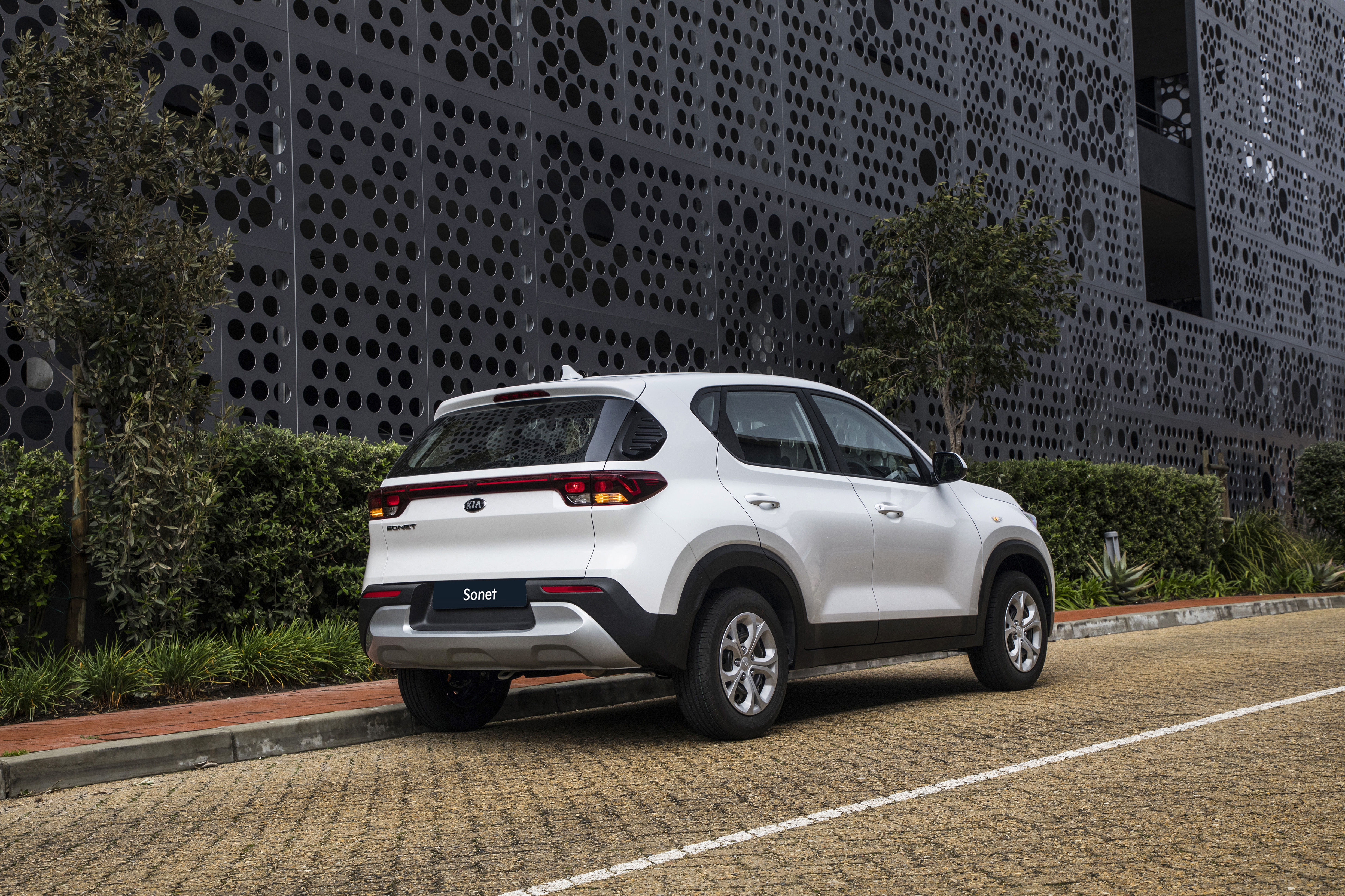 White Kia Sonet LX SUV parked by modern building 4K HD Wallpaper