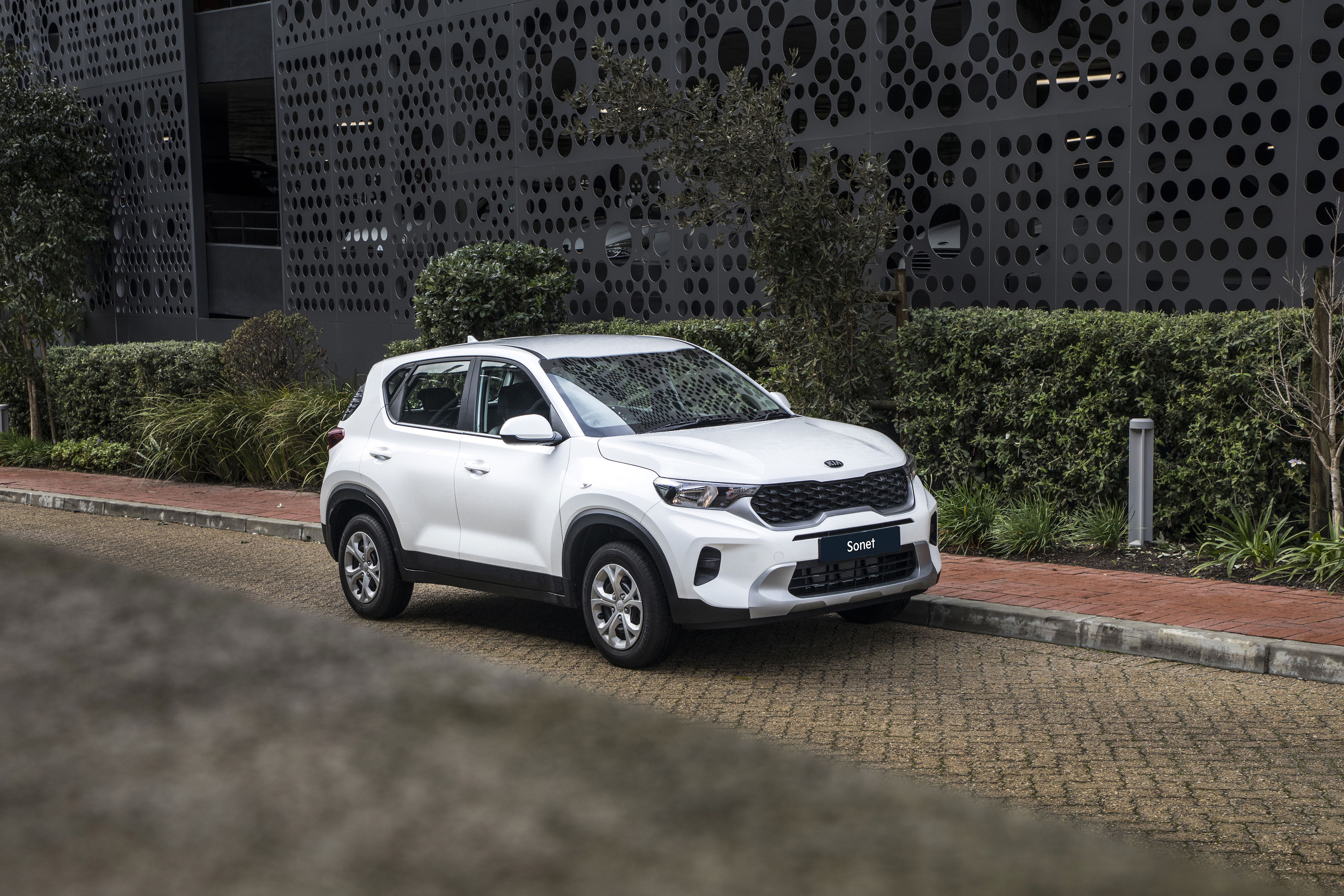 White Kia Sonet LX SUV parked on a street HD Wallpaper