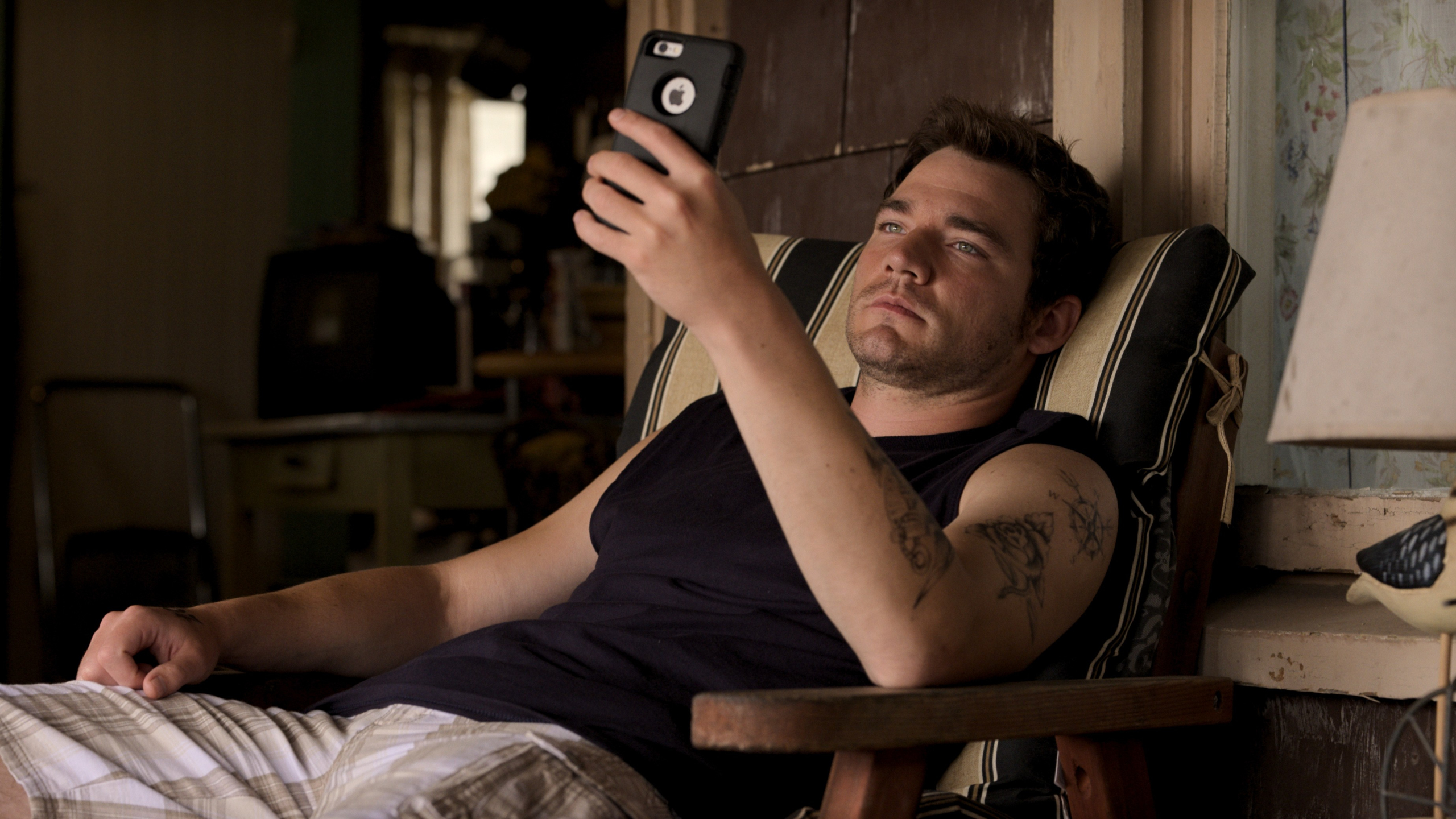 Daniel Durant looking at his iPhone in a chair HD Wallpaper