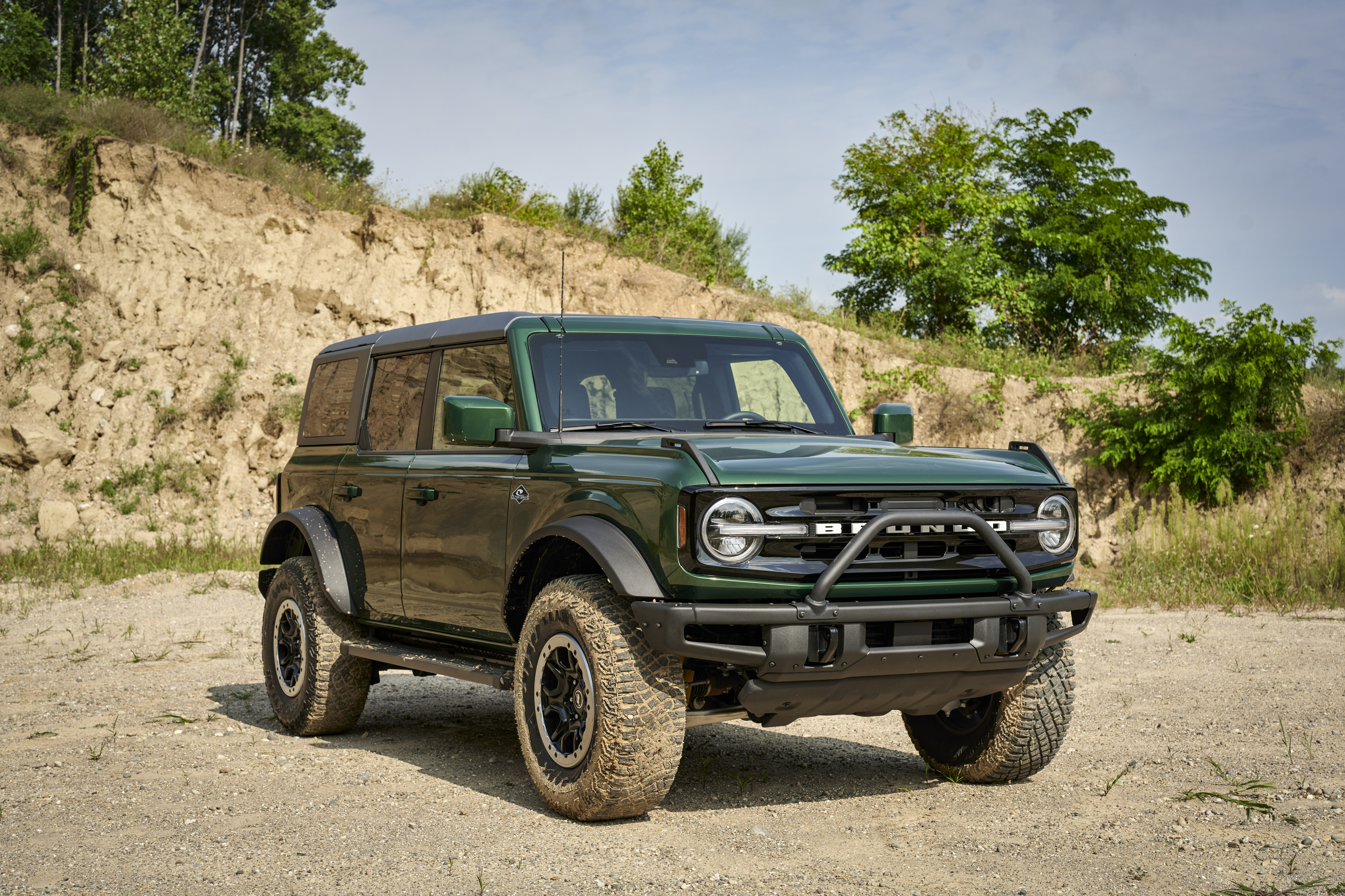 Green 2021 Ford Bronco 4-Door Outer Banks SUV on dirt road HD Wallpaper