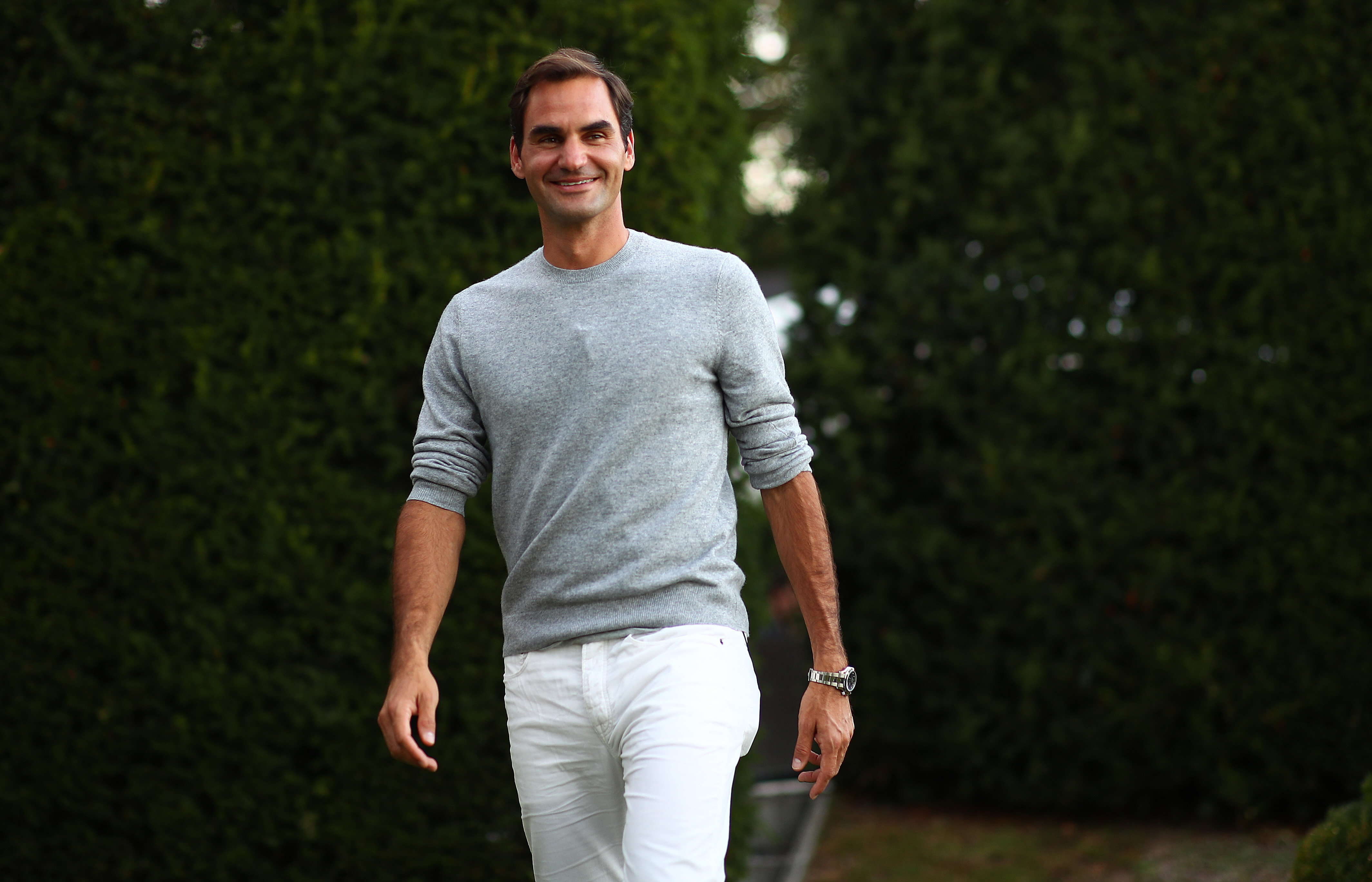 Roger Federer smiling and walking outdoors HD Wallpaper