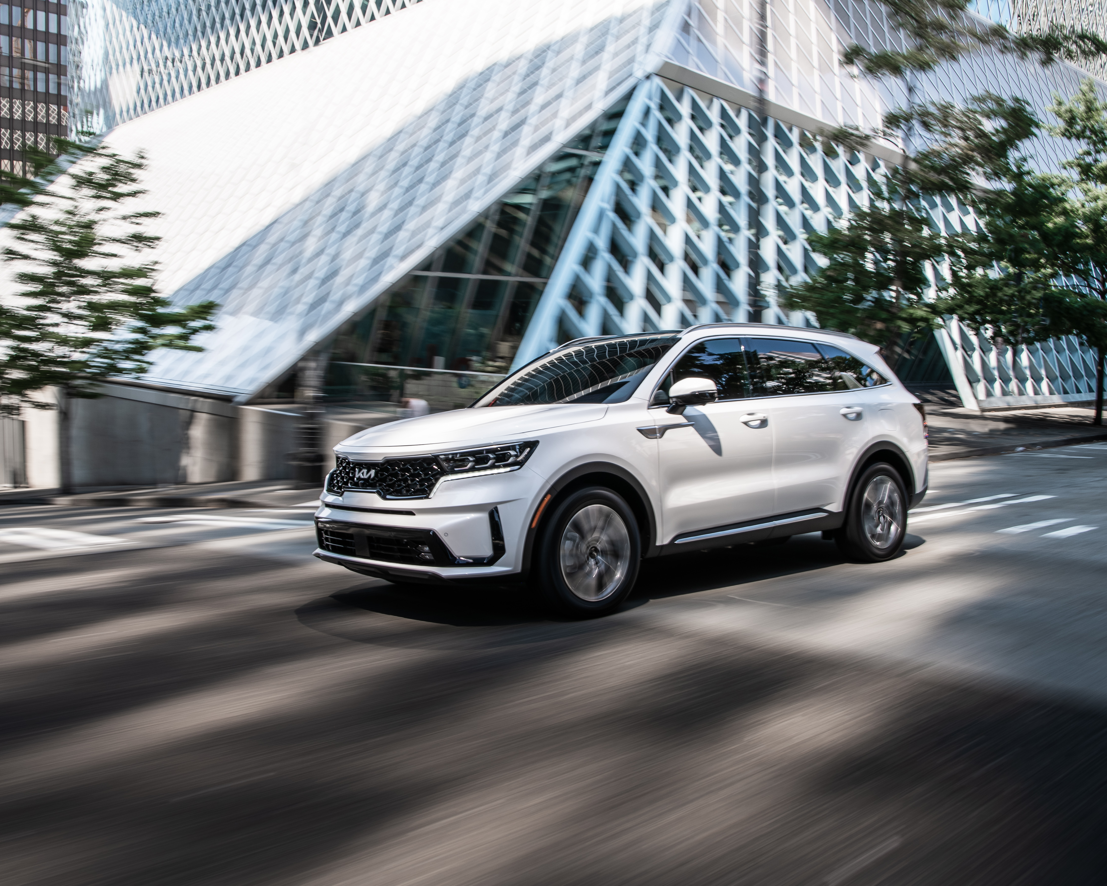 White Kia Sorento PHEV SUV driving through a modern city HD Wallpaper
