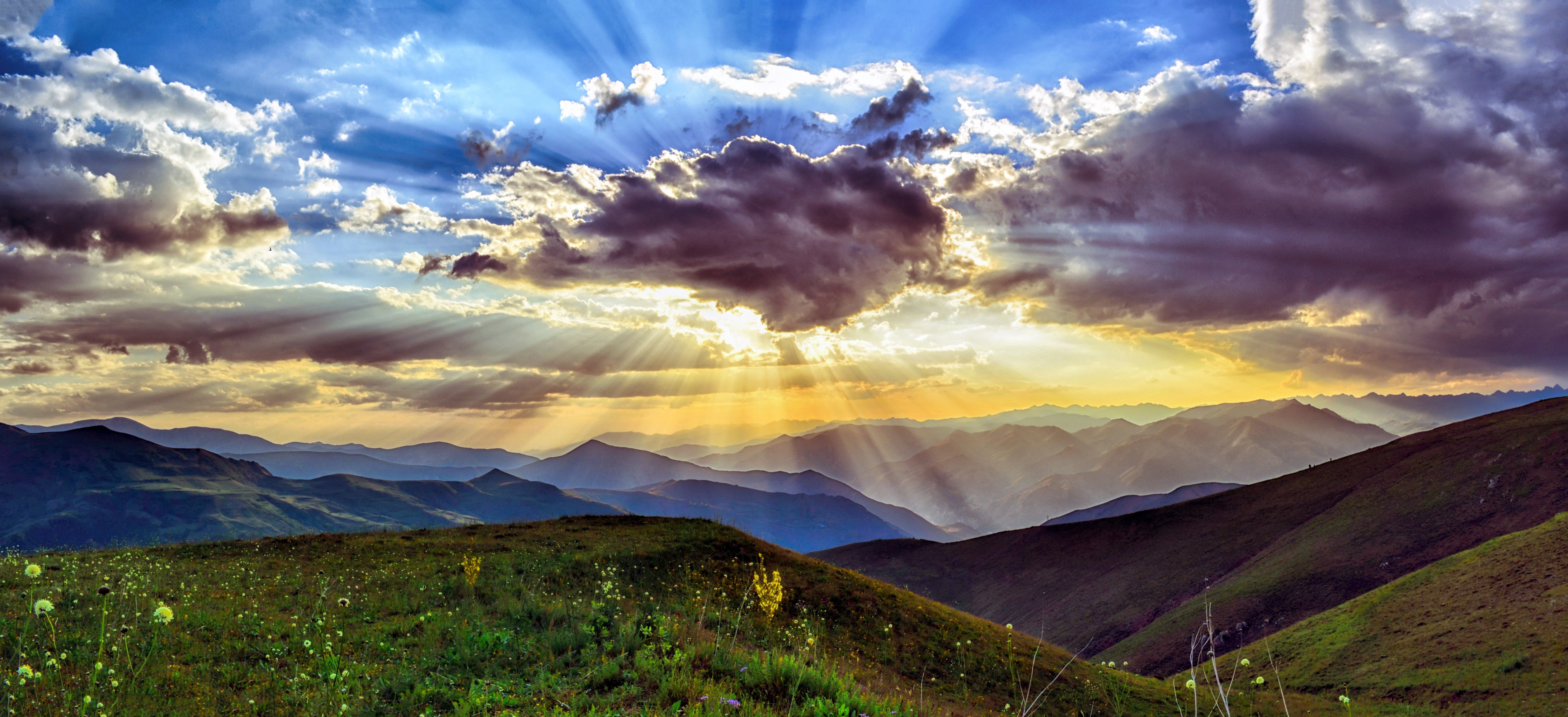 Golden sunbeams pierce dramatic sky over mountains HD Wallpaper