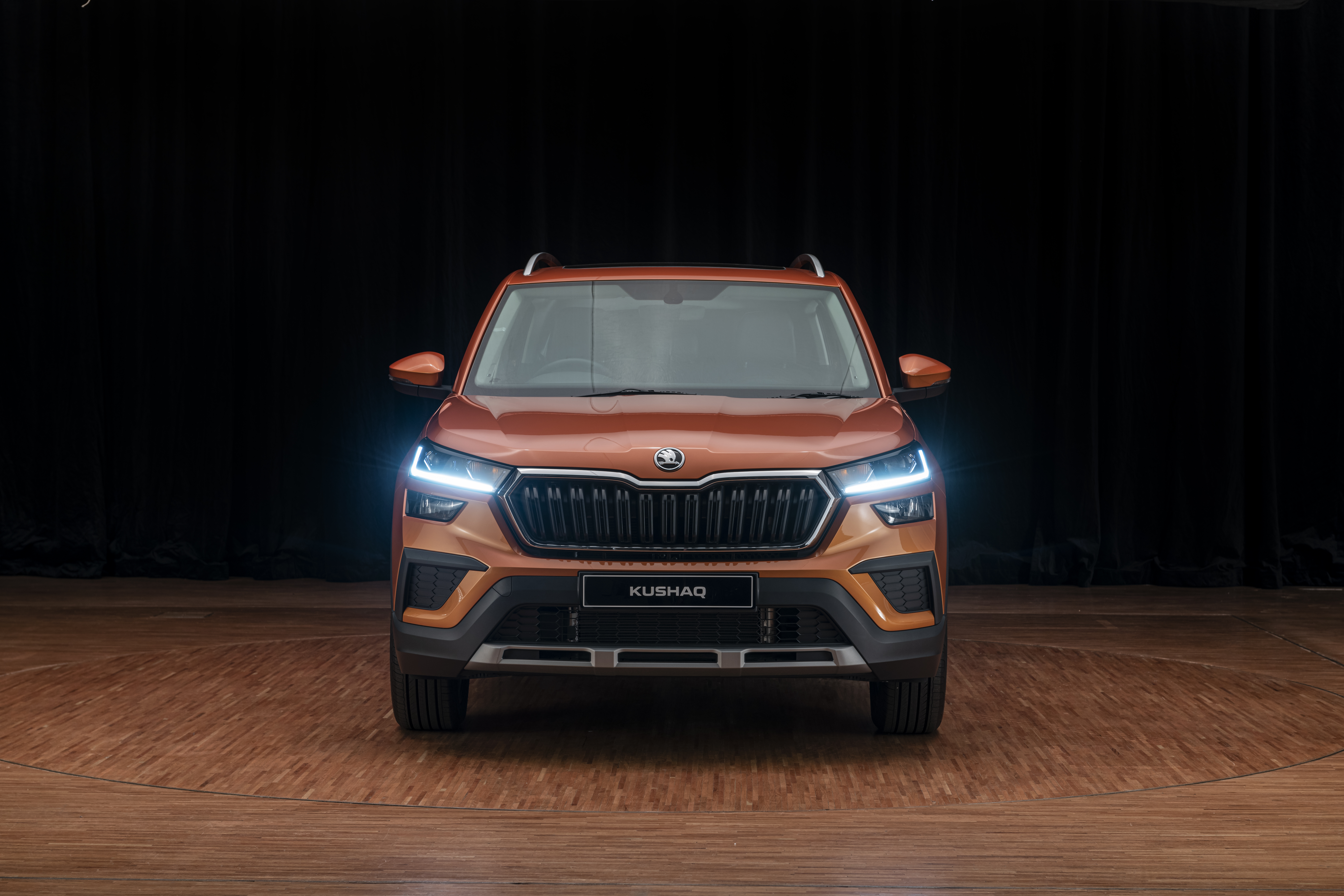 Orange Škoda Kushaq SUV with bright headlights HD Wallpaper