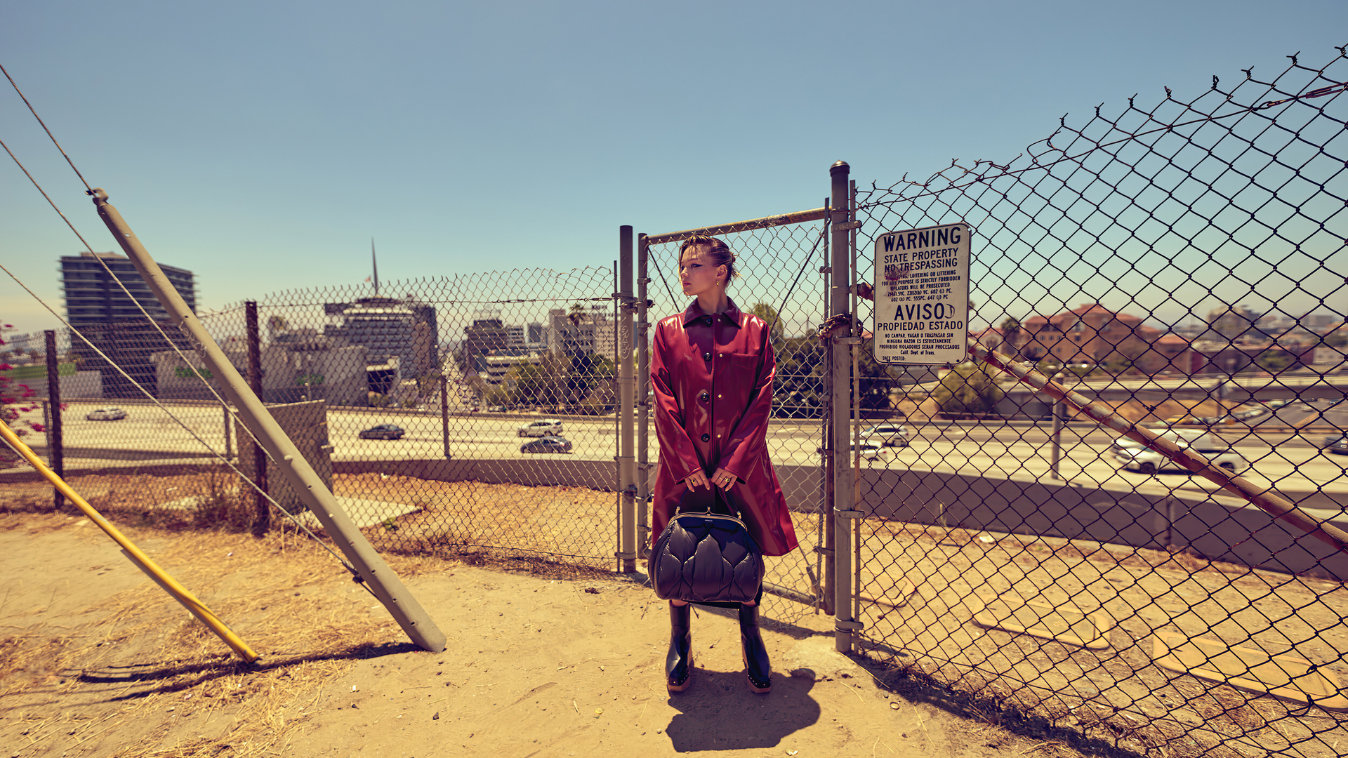 Olivia Holt in red coat by urban highway fence HD Wallpaper