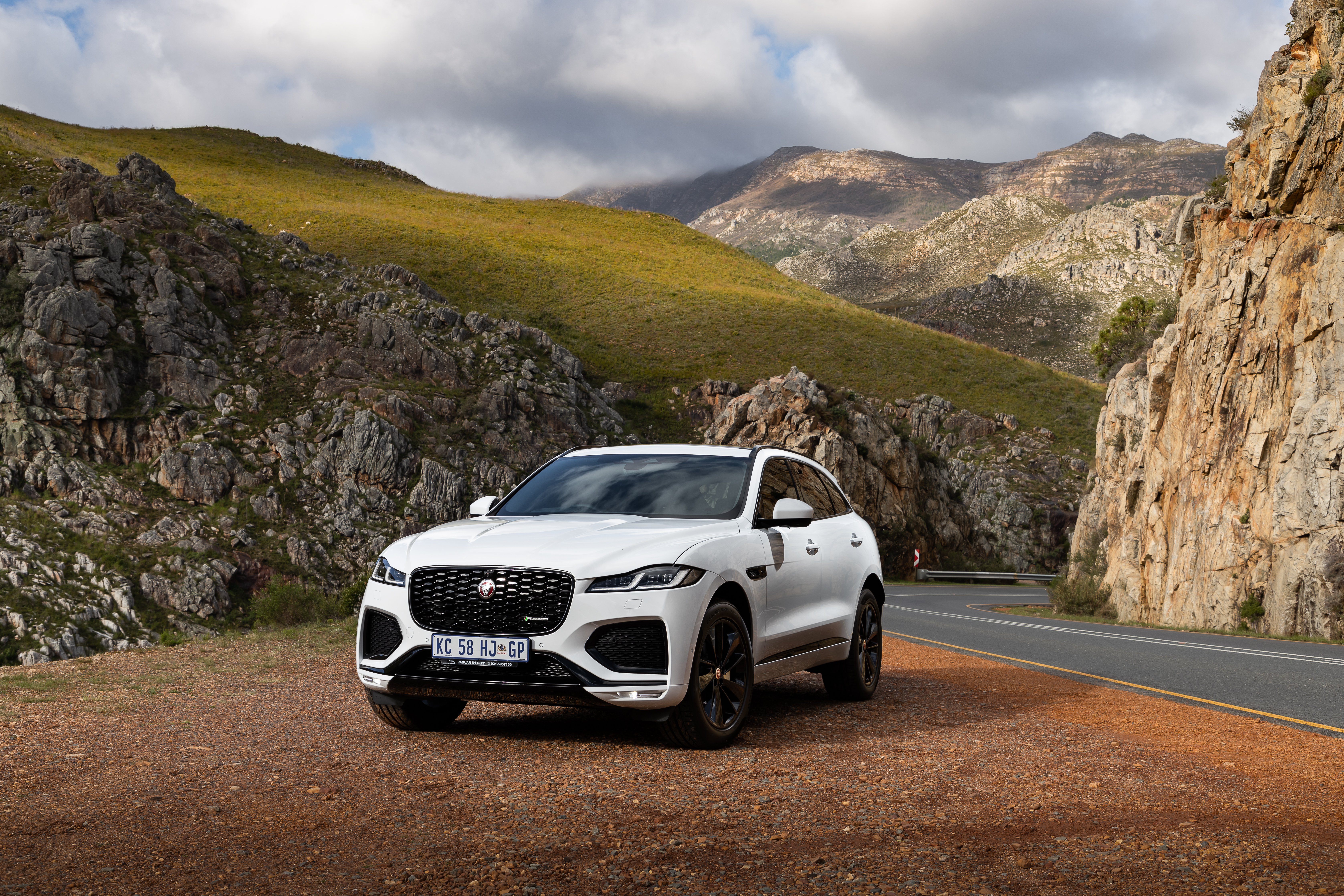 Luxury Jaguar F-Pace SUV on a scenic mountain road HD Wallpaper