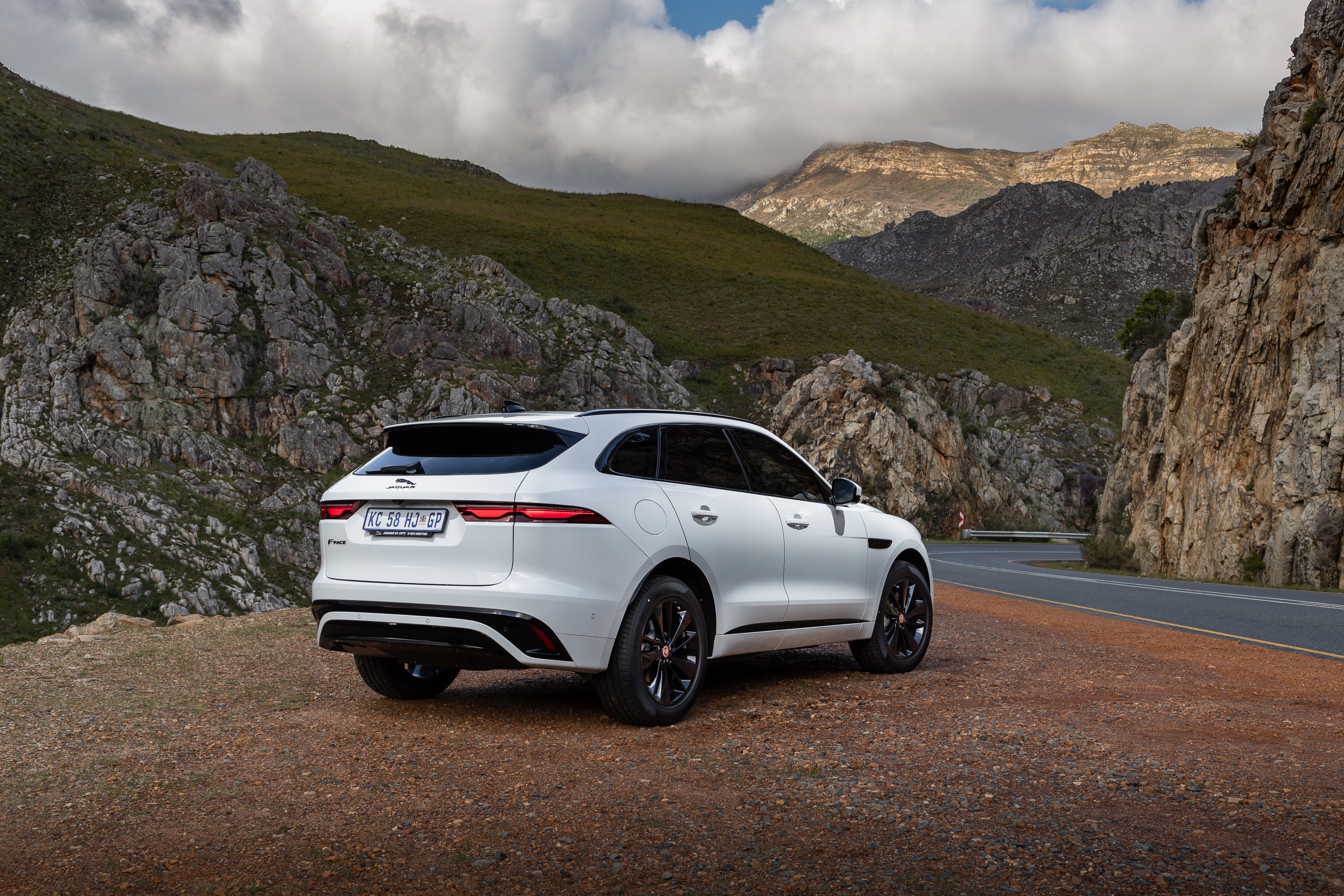 White Jaguar F-Pace SUV on a scenic mountain road HD Wallpaper