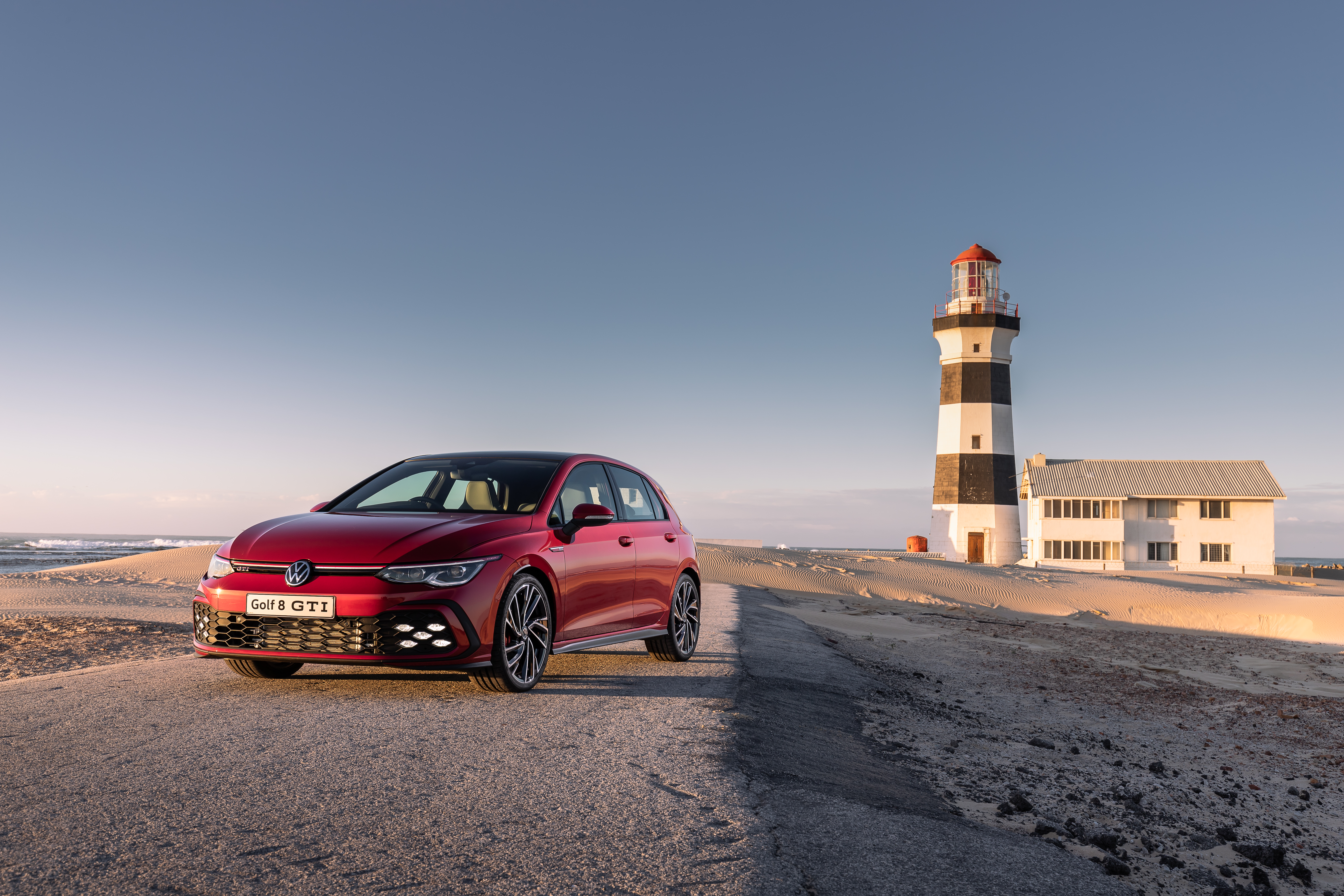 Volkswagen Golf GTI 4K on a coastal road with lighthouse HD Wallpaper