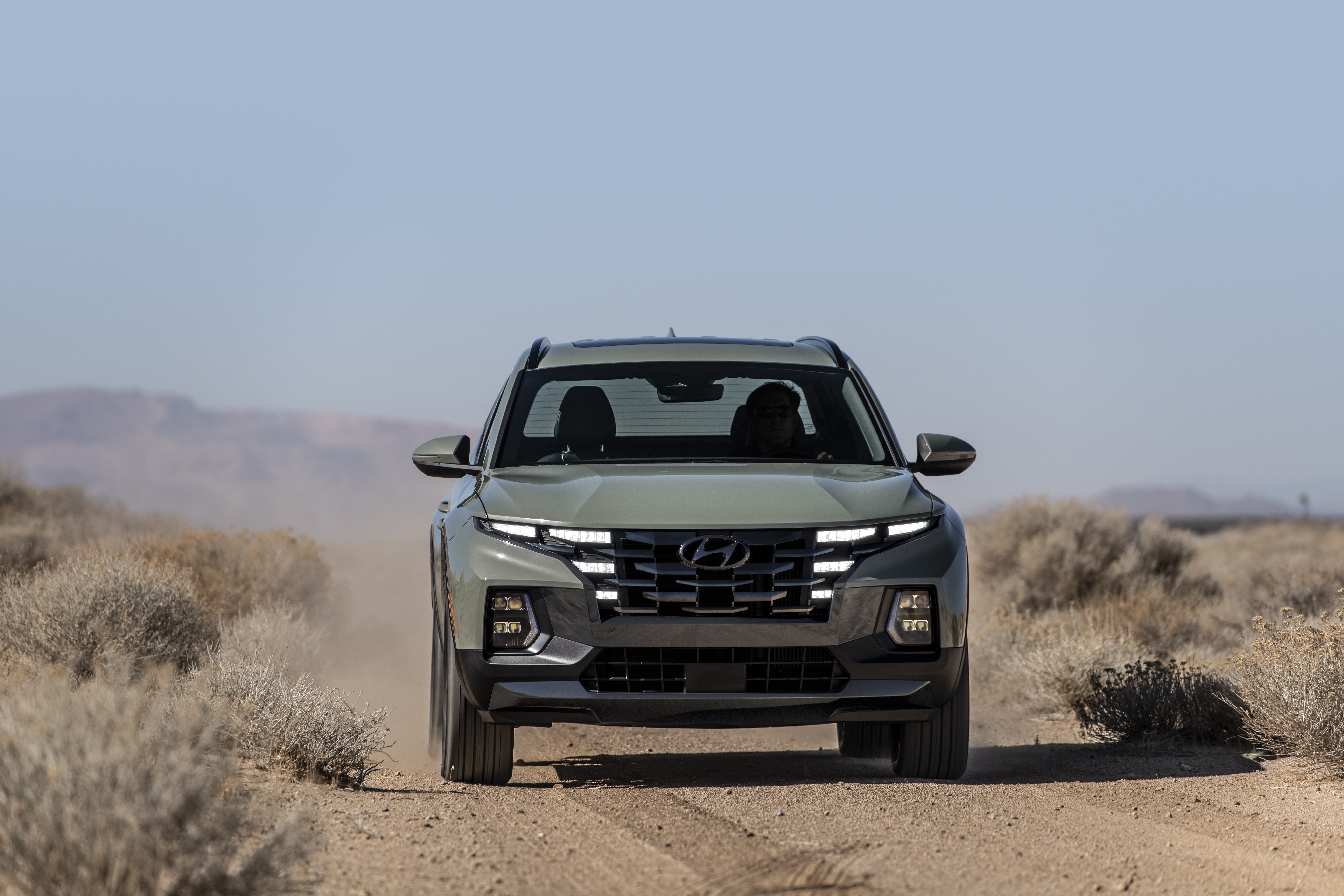 Hyundai Santa Cruz pickup driving on dusty desert road HD Wallpaper