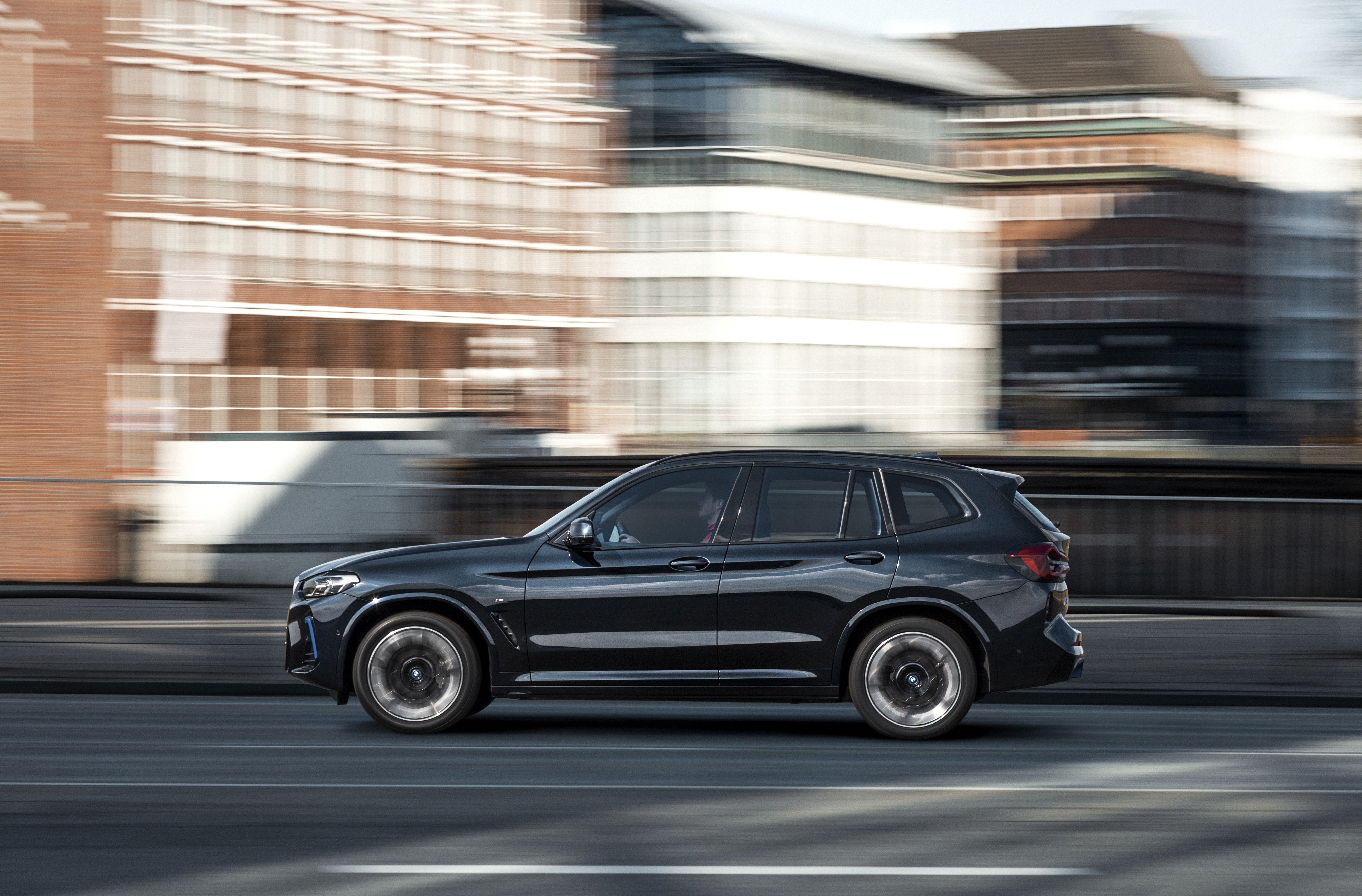 Black BMW iX3 M Sport Electric SUV driving in city HD Wallpaper