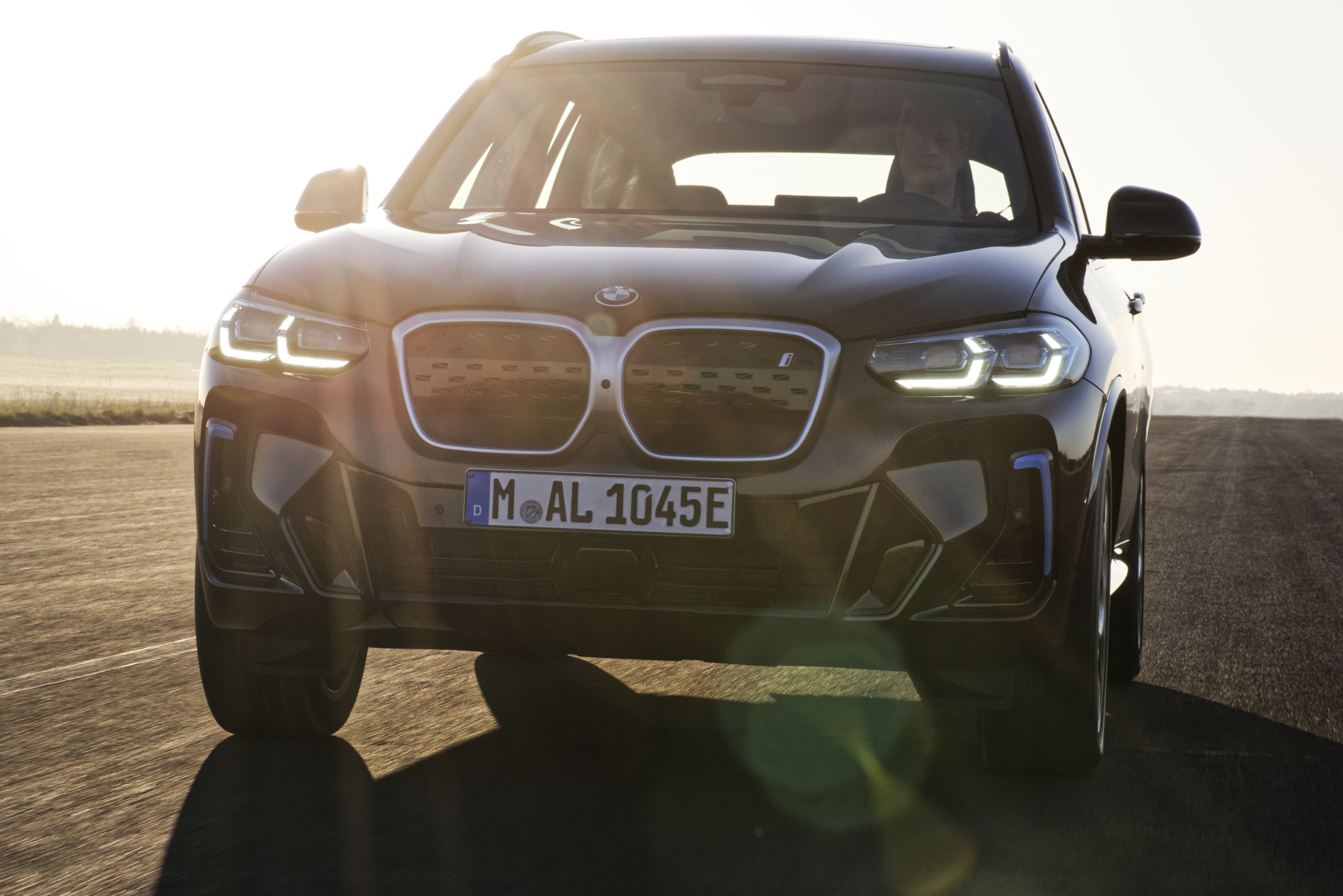 Black BMW iX3 M Sport electric SUV on a sunny road HD Wallpaper